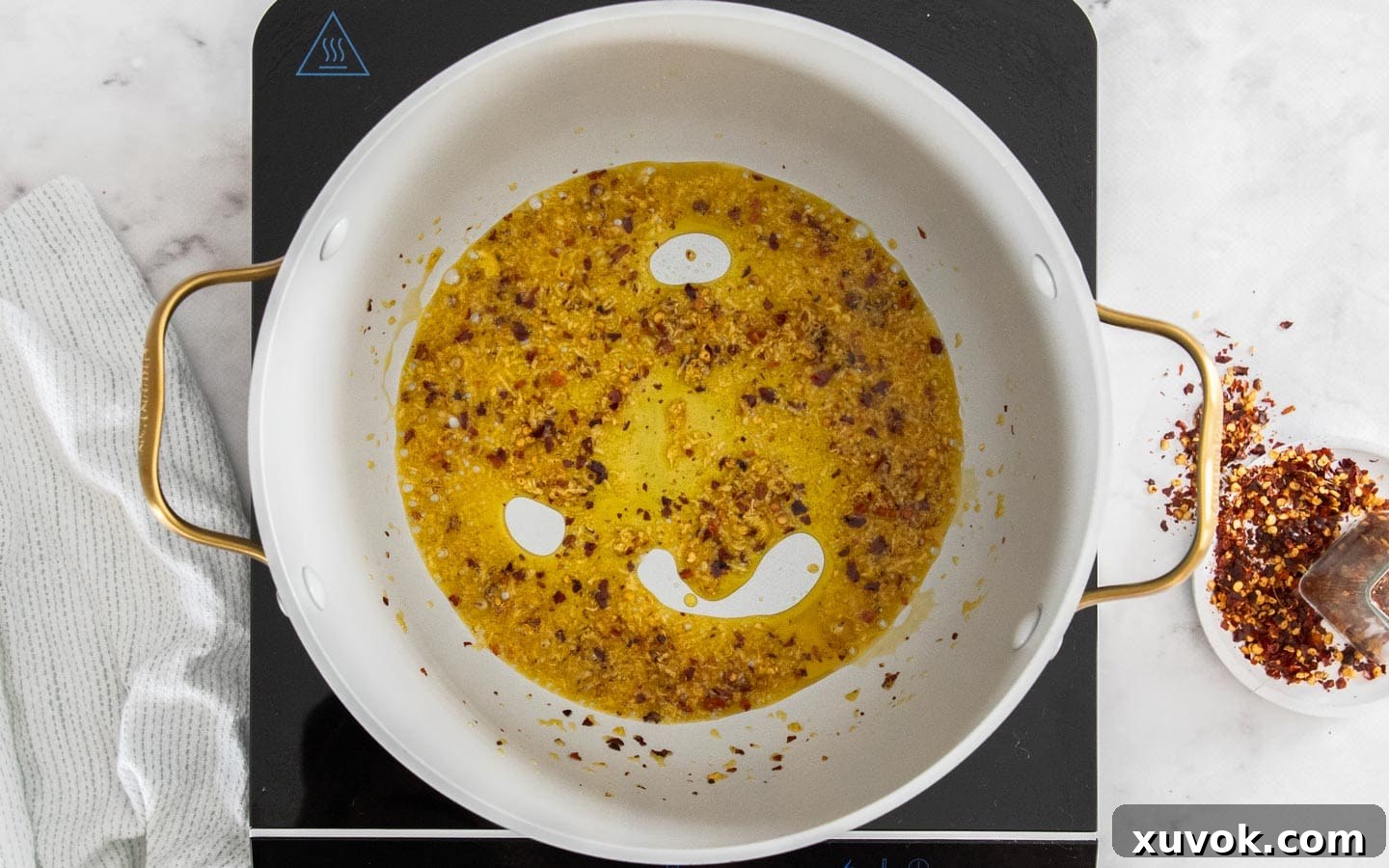 Garlic and chili flakes gently cooking in olive oil in a pan, filling the air with their aroma.