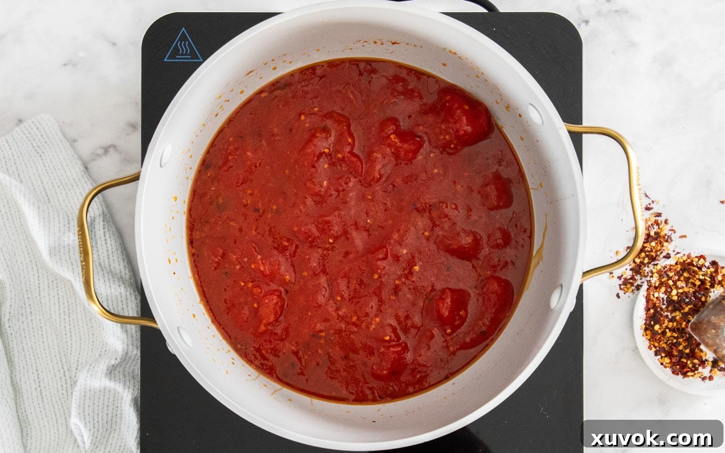 Whole peeled tomatoes and tomato paste freshly added to the pan with garlic and chili, before simmering.