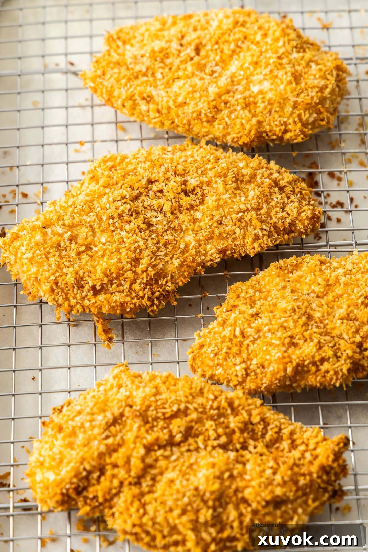 4 panko chicken schnitzels on a wire rack, freshly baked and golden.