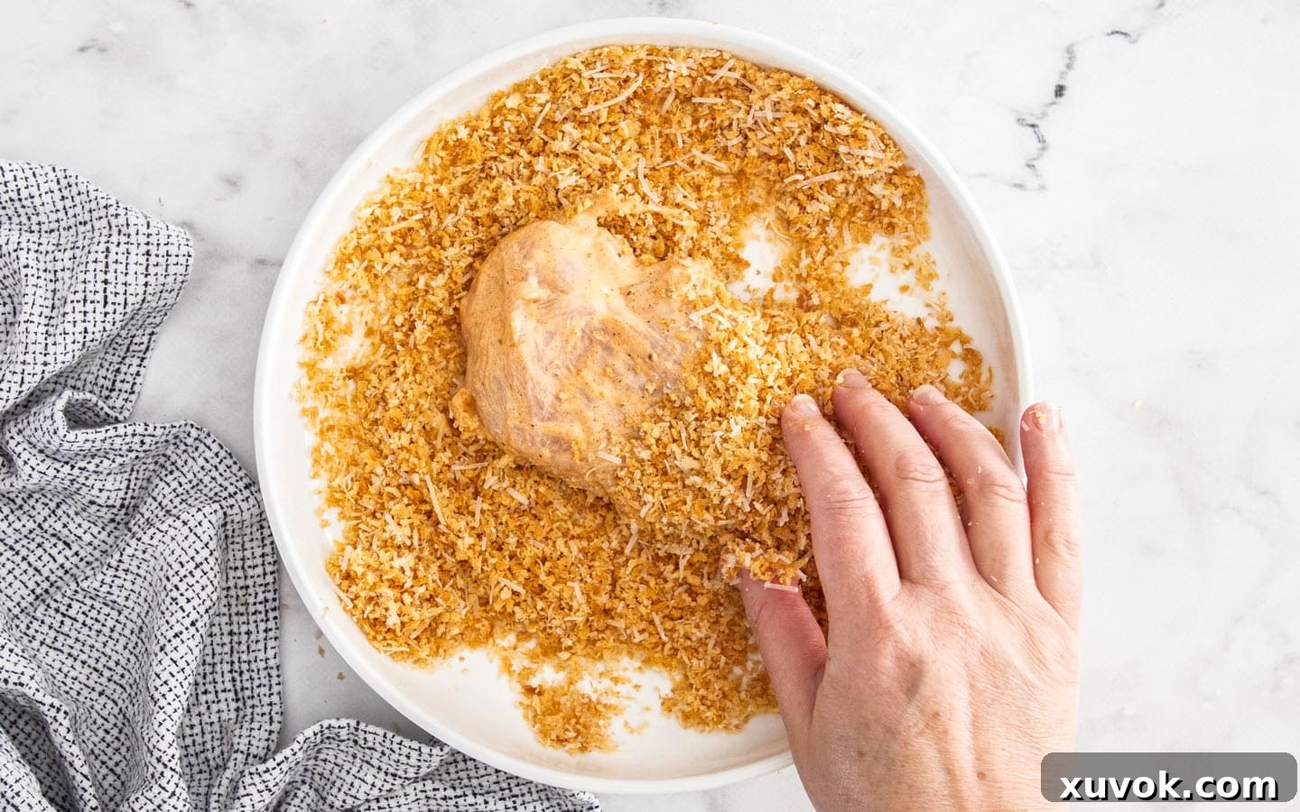 Coating the chicken in panko crumbs, pressing them firmly onto the surface.