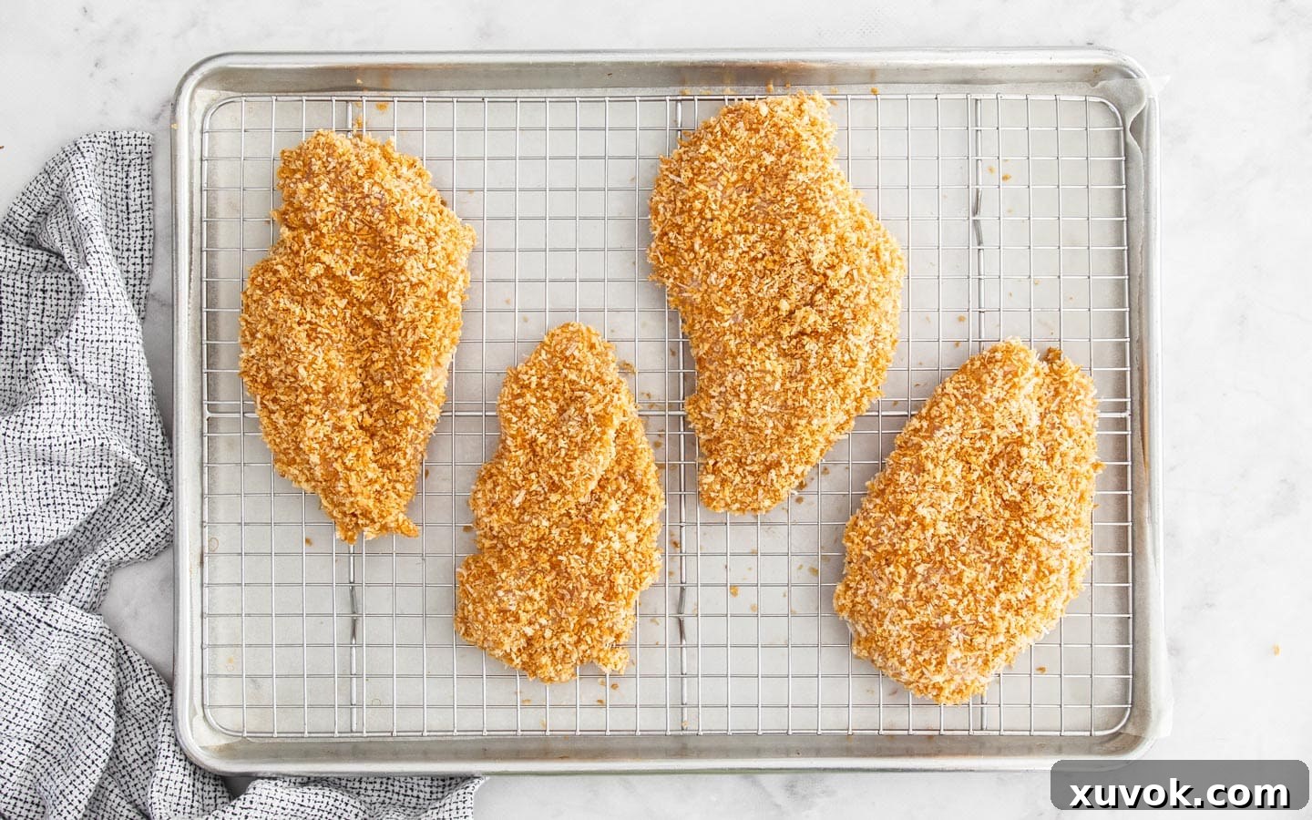 The crumbed chicken on a wire rack over a baking tray, ready to be baked.