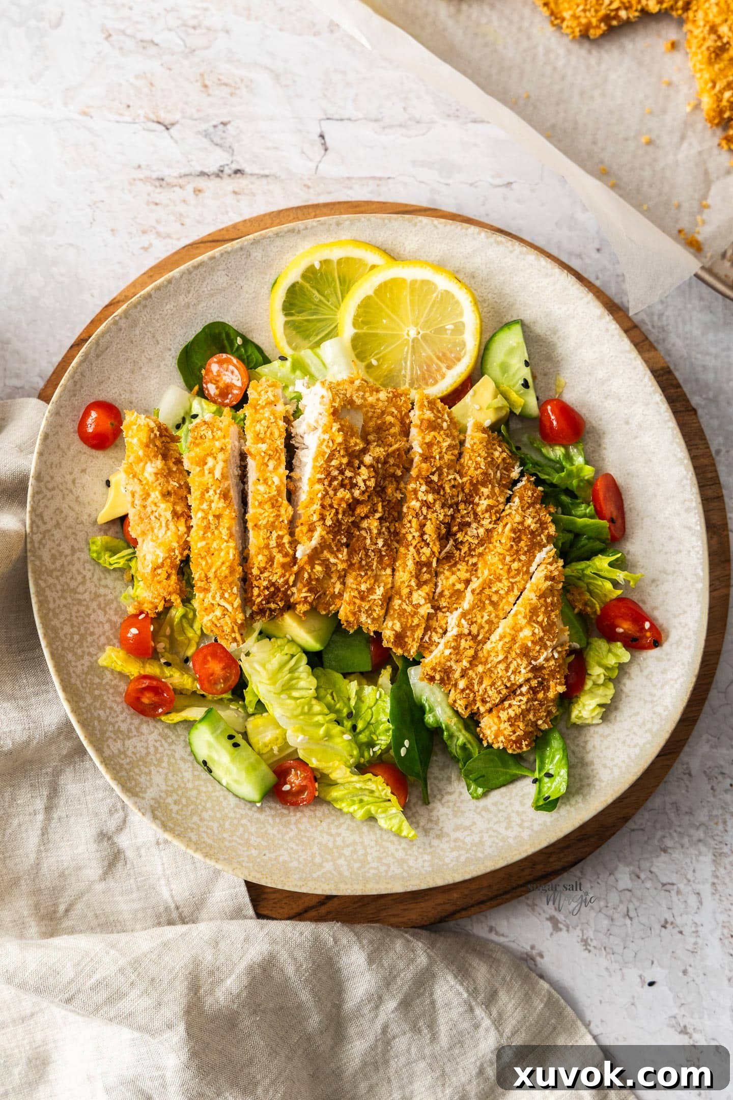 Panko crumbed chicken served on a fresh green salad on a plate.