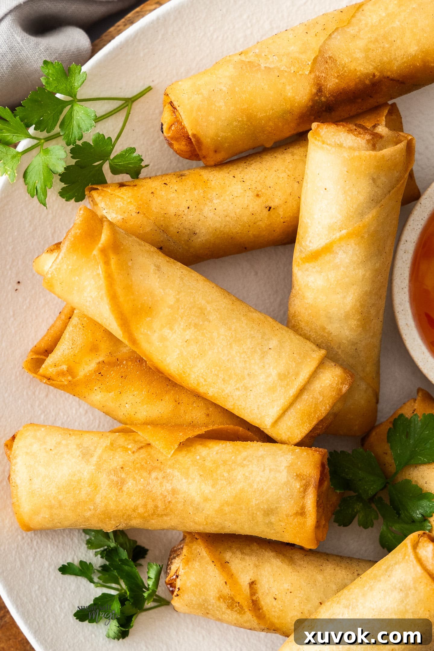 Closeup of 9 spring rolls on a plate, golden and crispy.