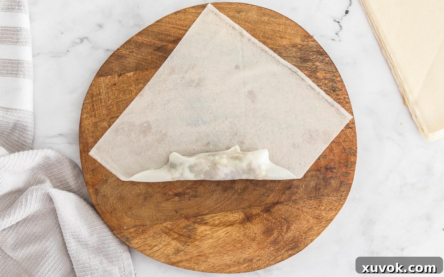 The bottom corner of the spring roll wrapper folded over the prawn filling.