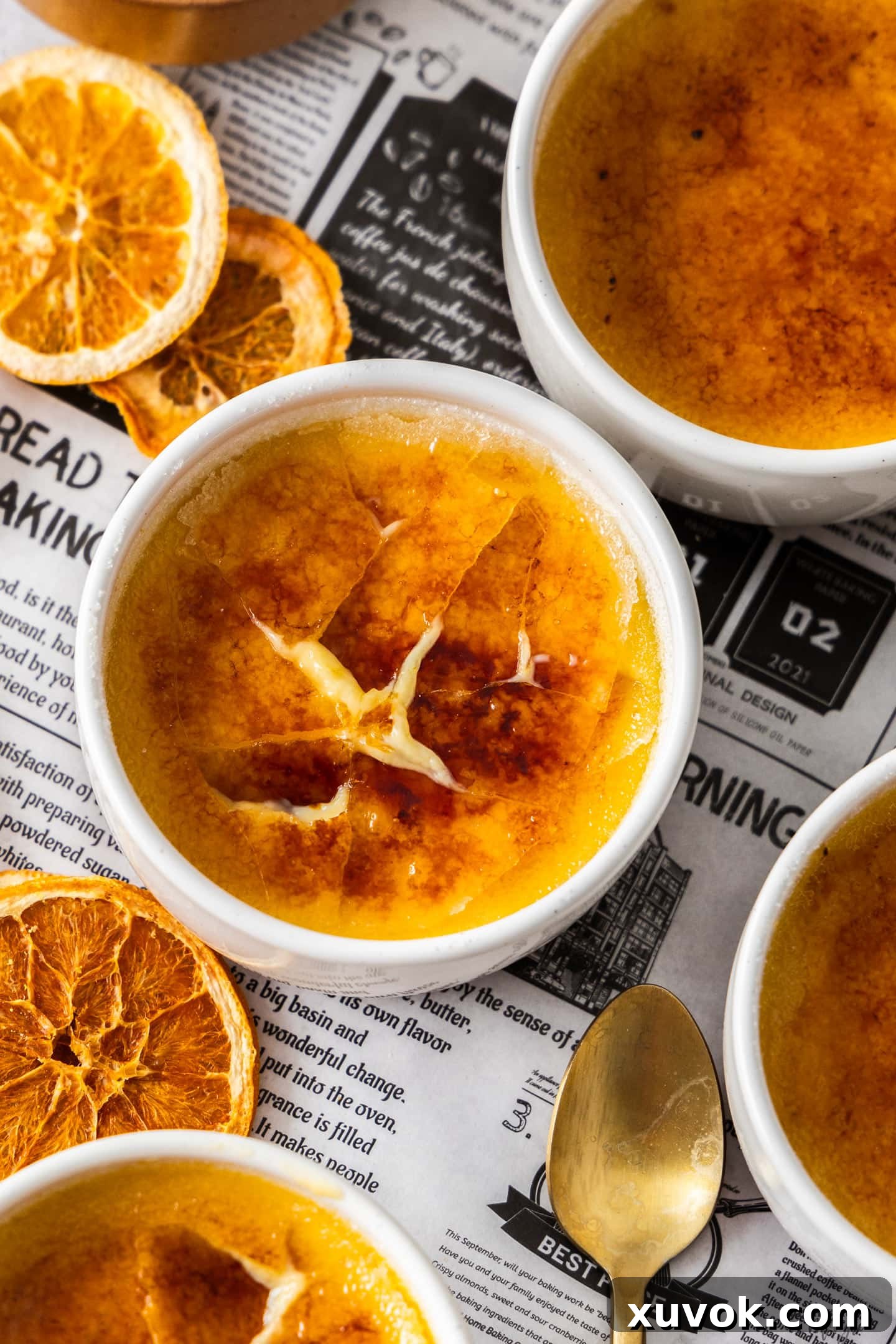 A close-up of an orange creme brulee with its crispy caramelized sugar topping already cracked into pieces, ready to eat.