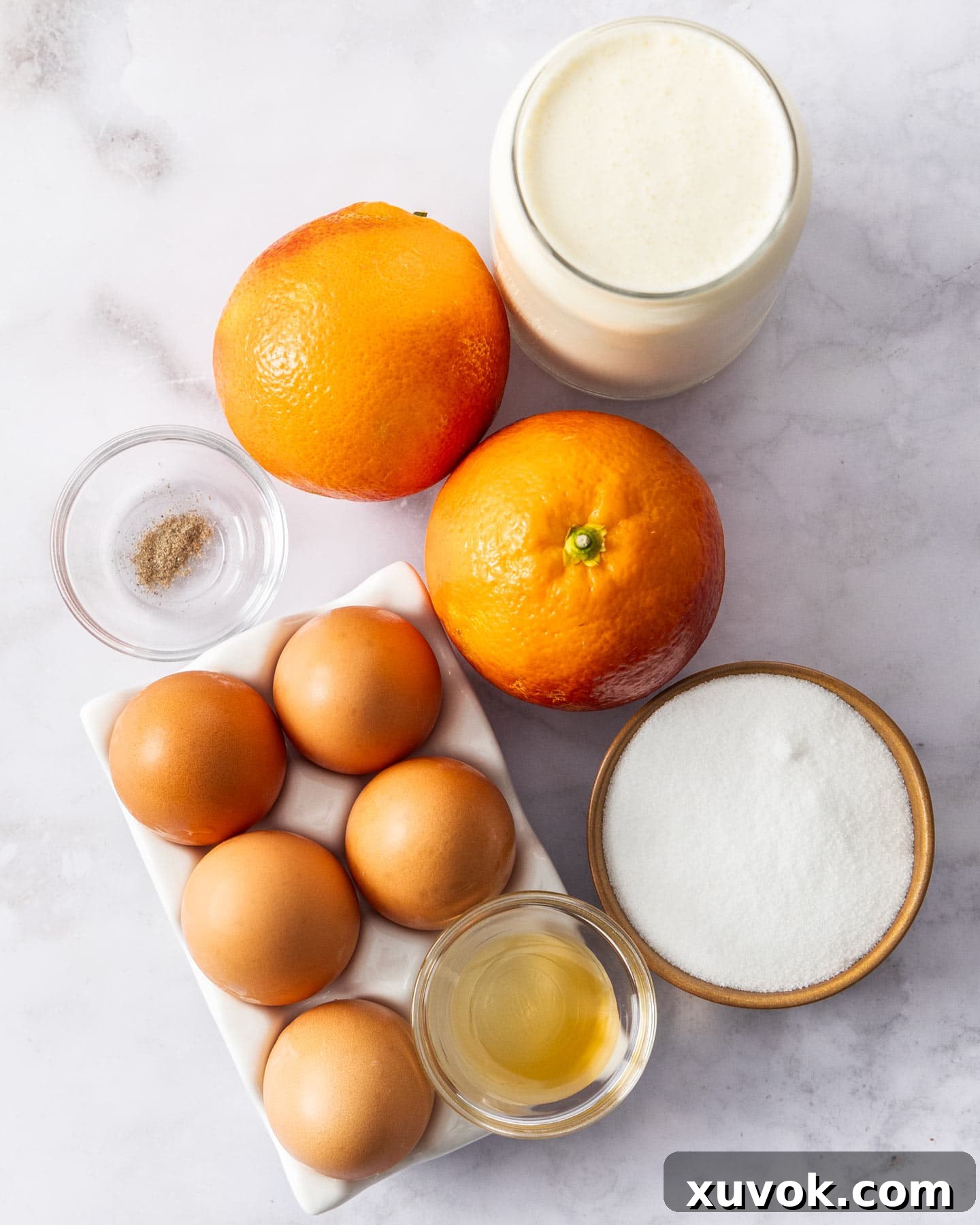 Fresh oranges, egg yolks, cream, sugar, vanilla, and cardamom laid out as ingredients for orange creme brulee.