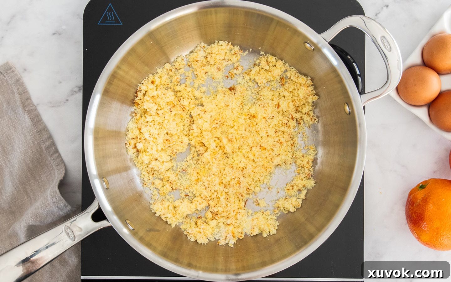 Close-up of orange zest and superfine sugar being blended together by hand in a saucepan.