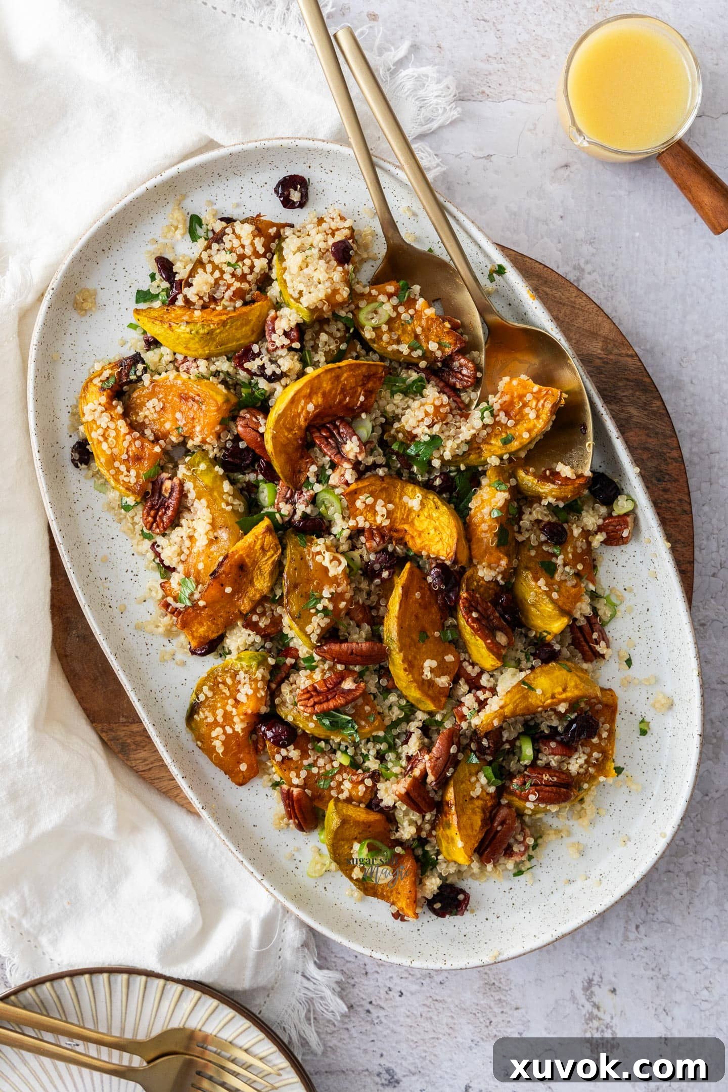 Top-down view of a vibrant pumpkin quinoa salad served on an oblong serving dish, highlighting its rich colors and inviting textures. The roasted pumpkin, fluffy quinoa, and red cranberries are clearly visible.