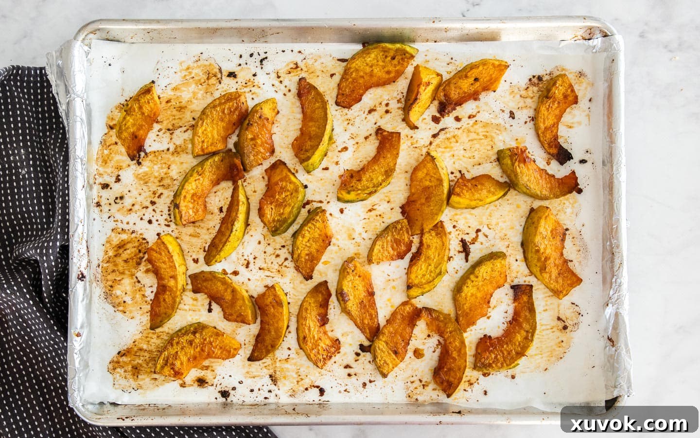 Perfectly baked pumpkin pieces on a baking sheet, golden brown and caramelized, ready to be added to the salad.