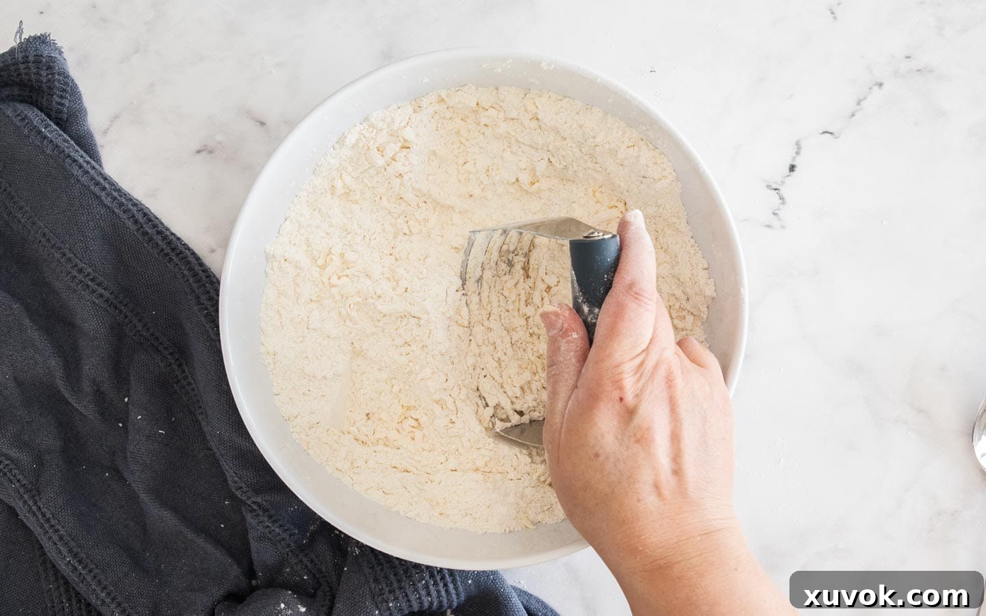 Blending cold butter into the flour mixture using a pastry blender.