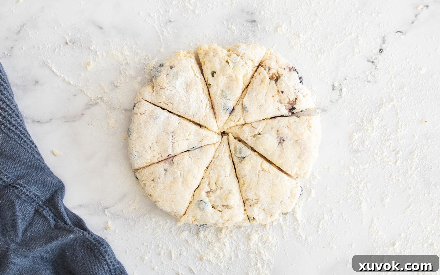 A round of scone dough perfectly cut into 8 triangular wedges on a floured surface.