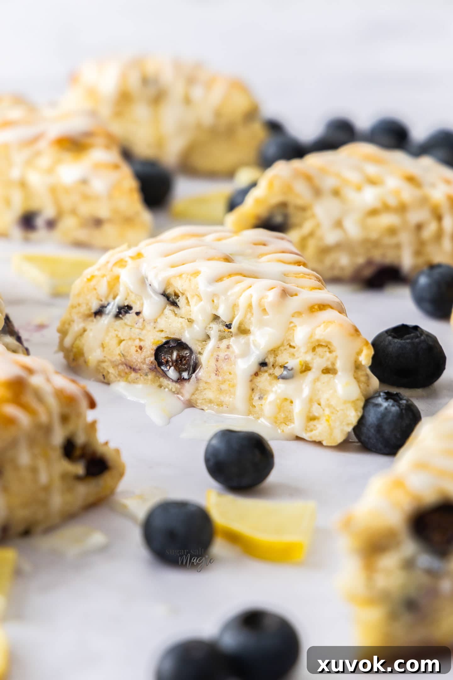 Closeup of the side of a blueberry and lemon scone, showcasing its tender crumb and visible blueberries.