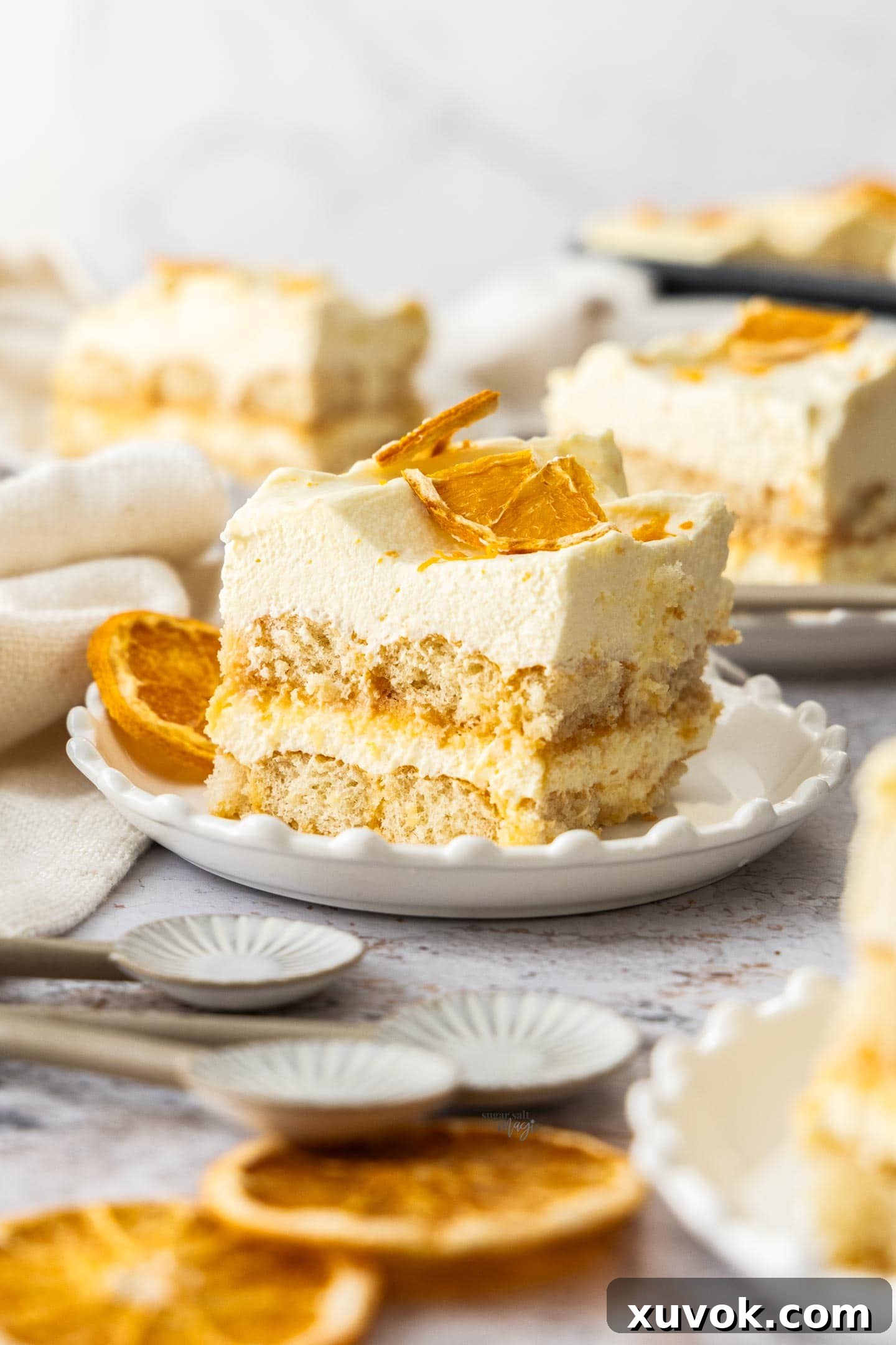 A close-up view of a perfectly sliced orange tiramisu on a white plate, showcasing its creamy layers and orange zest garnish.