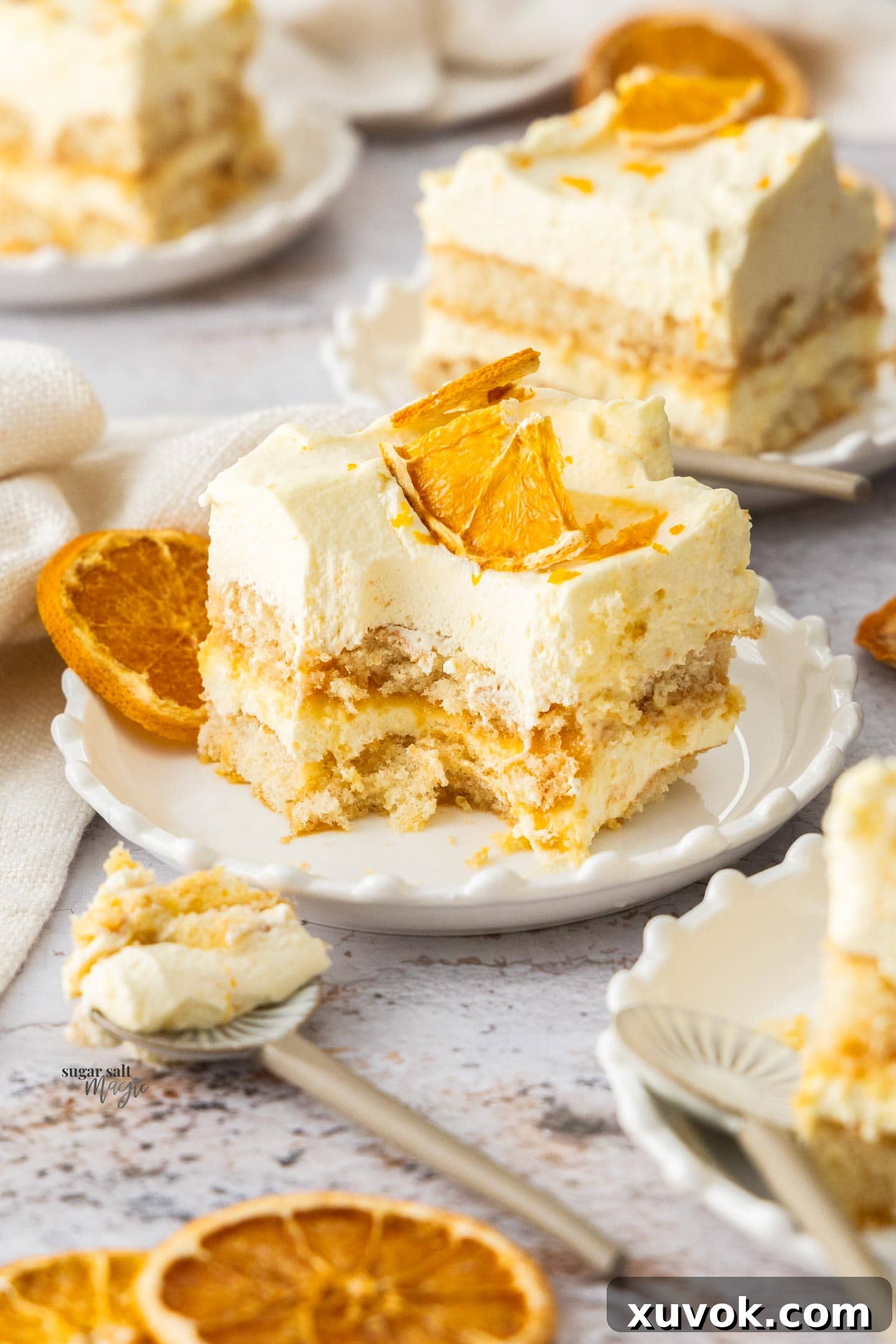 A tantalizing slice of orange tiramisu with a small scoop taken out, revealing the creamy and biscuit layers.