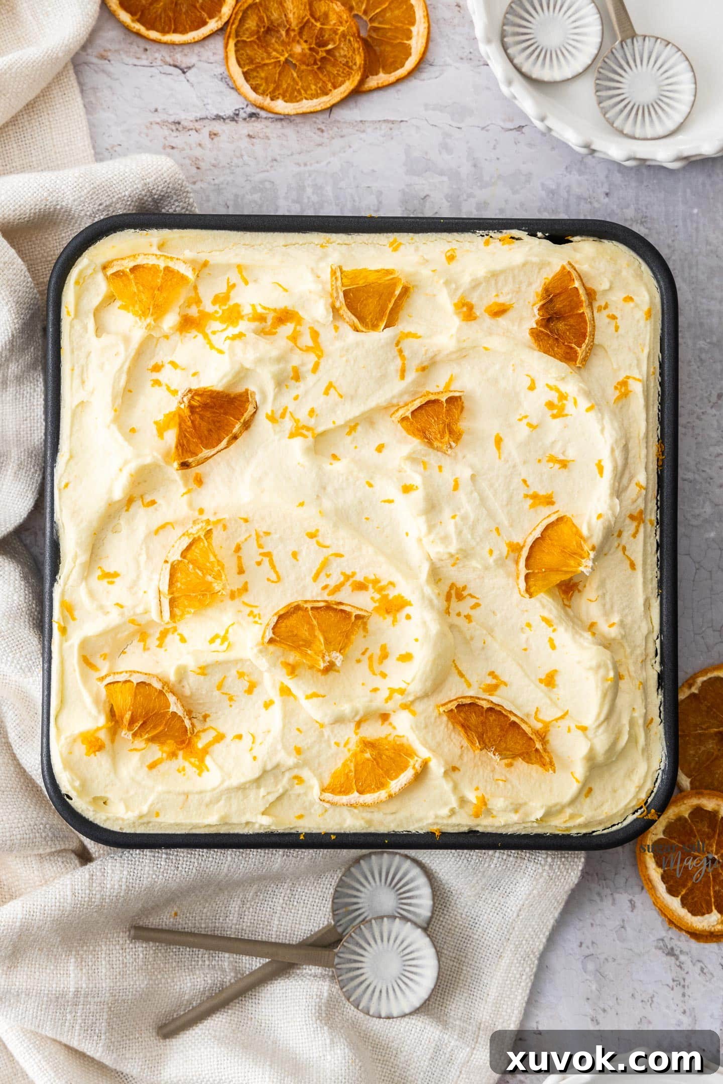 A top-down view of the freshly assembled orange tiramisu sitting in a square baking pan, ready for chilling and serving.