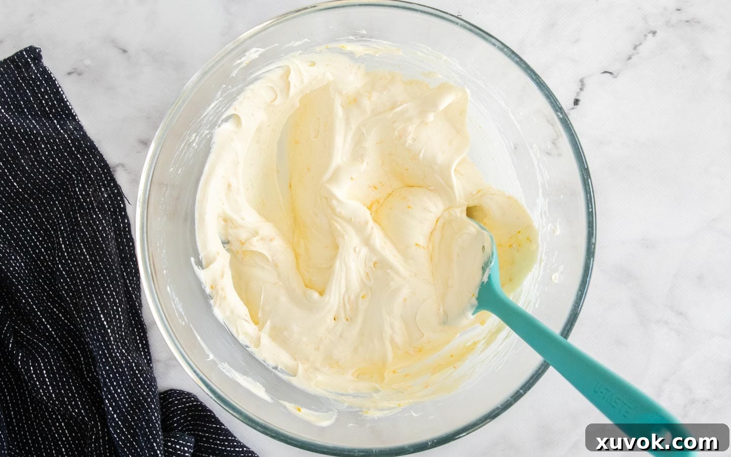 A bowl containing the smooth, light yellow mascarpone mixture, subtly infused with orange zest.