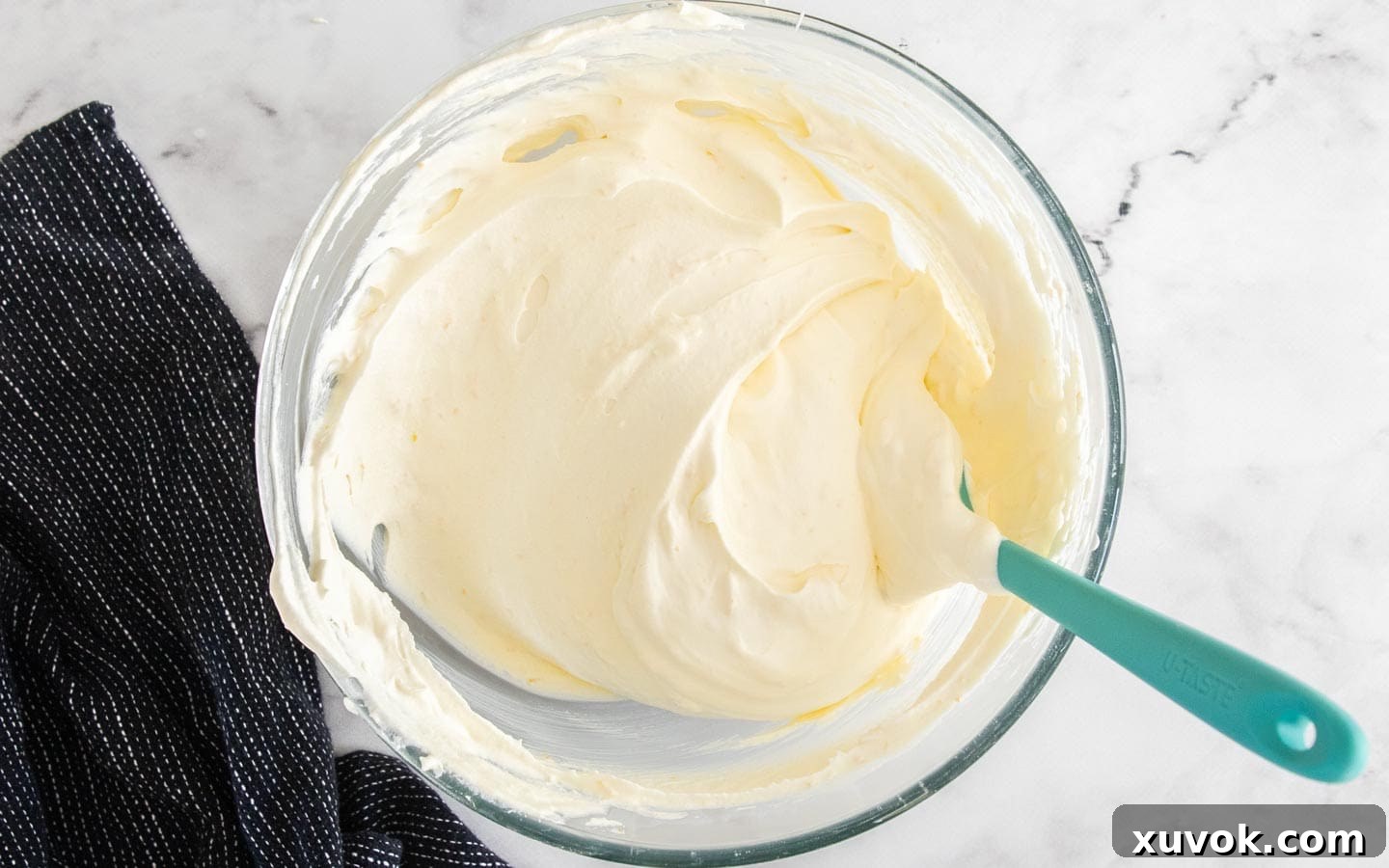 The two cream mixtures, whipped cream and mascarpone, gently folded together in a bowl, creating a smooth, airy tiramisu filling.