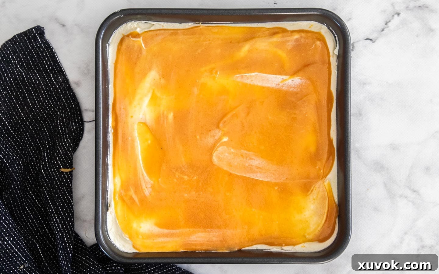 A vibrant layer of glossy orange curd spread smoothly over the mascarpone cream in the tiramisu, adding an intense citrus flavor.