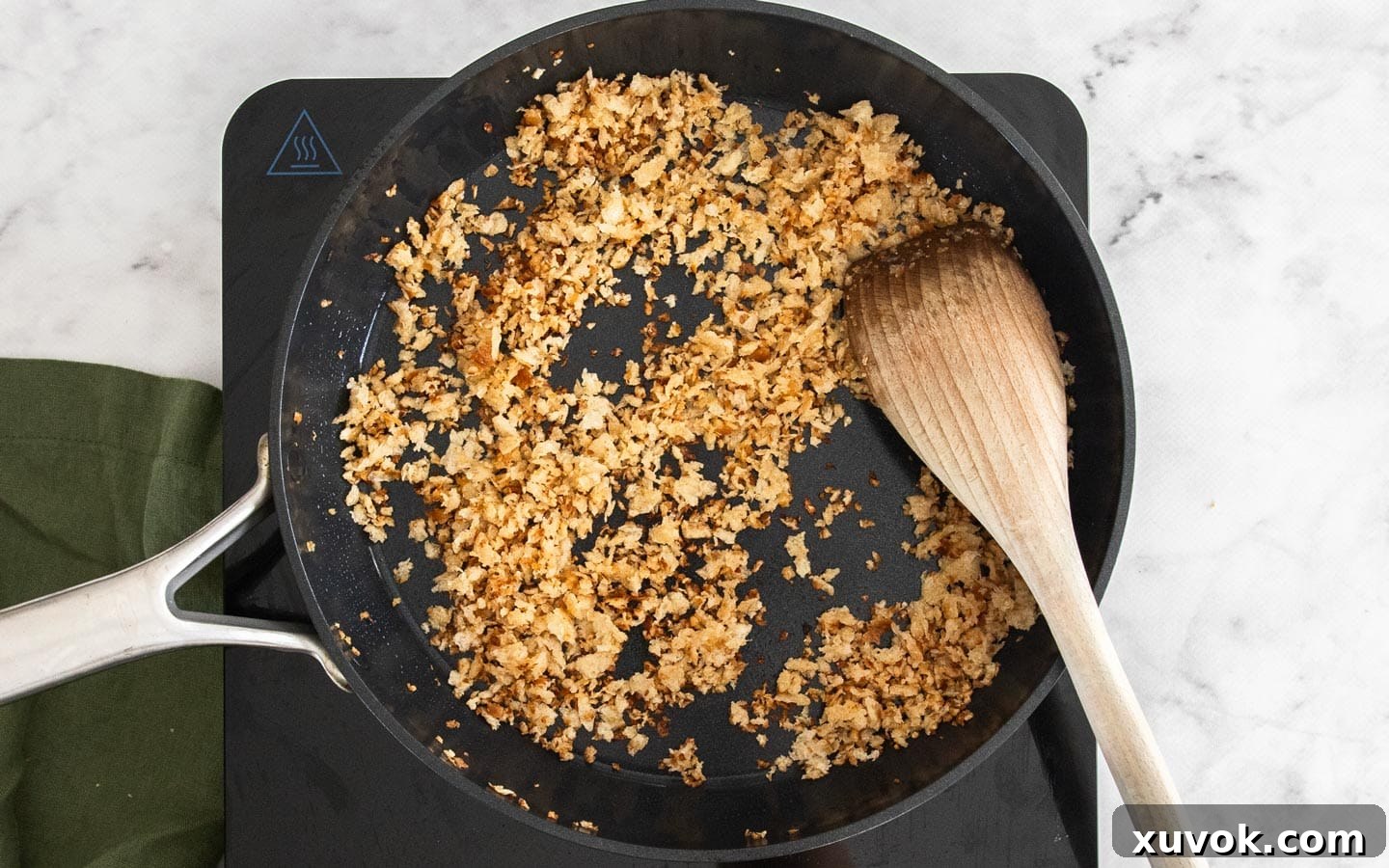 A close-up of golden-brown toasted breadcrumbs mixed with fragrant garlic, perfectly cooked and shimmering in a frying pan.