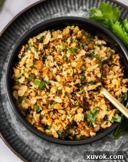 Top-down view of a small black bowl filled with golden, crunchy pangrattato, garnished with fresh parsley.