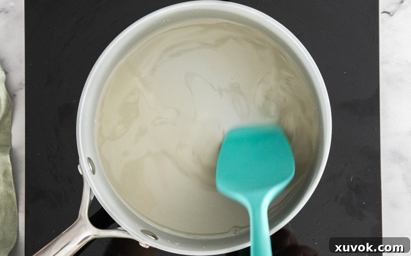 Stirring sugar into the gelatin and water mixture in a saucepan over low heat.