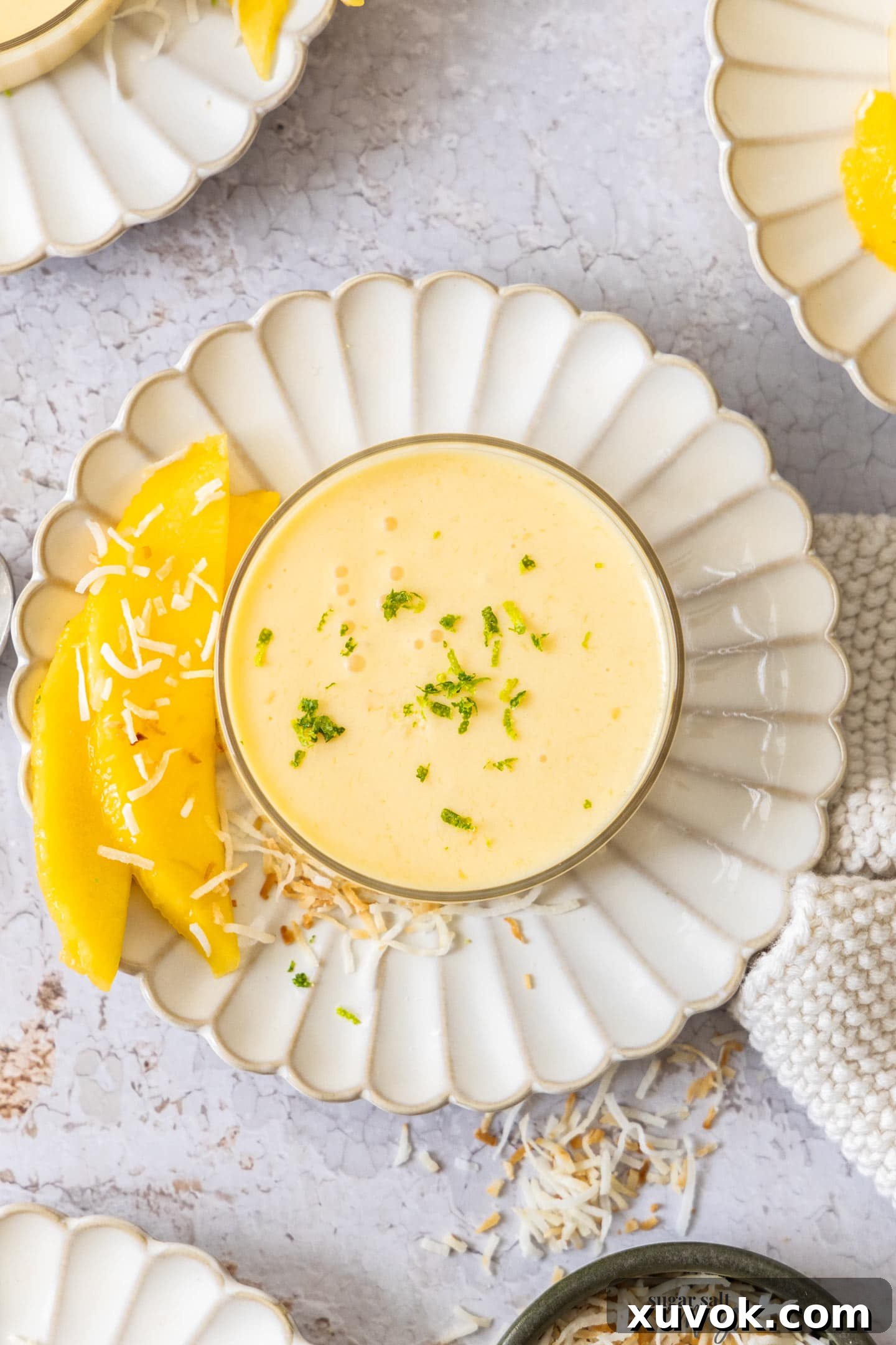 Top down view of mango panna cotta in a glass, garnished with a sprig of mint.
