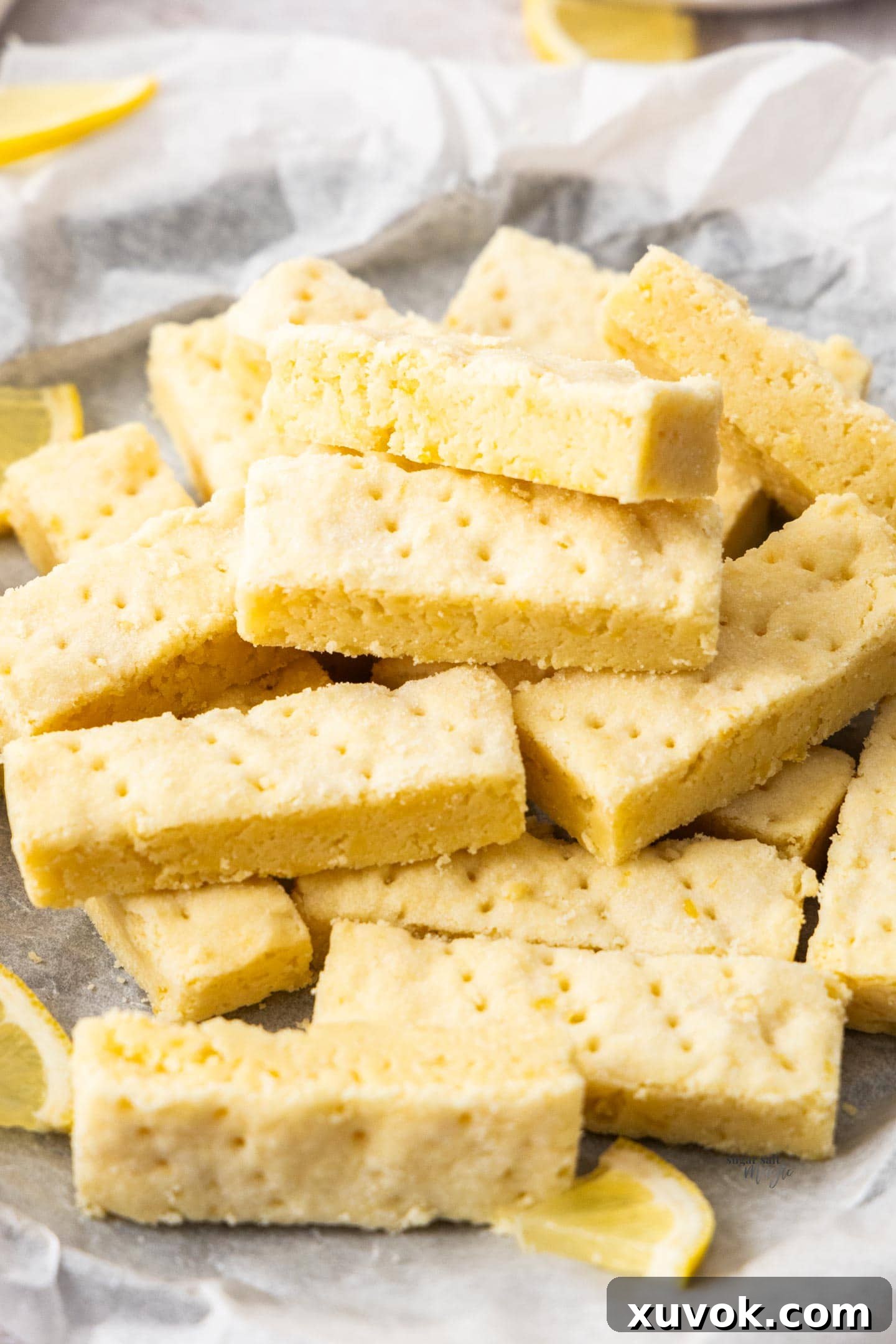 A pile of lemon shortbread cookies on a sheet of baking paper.
