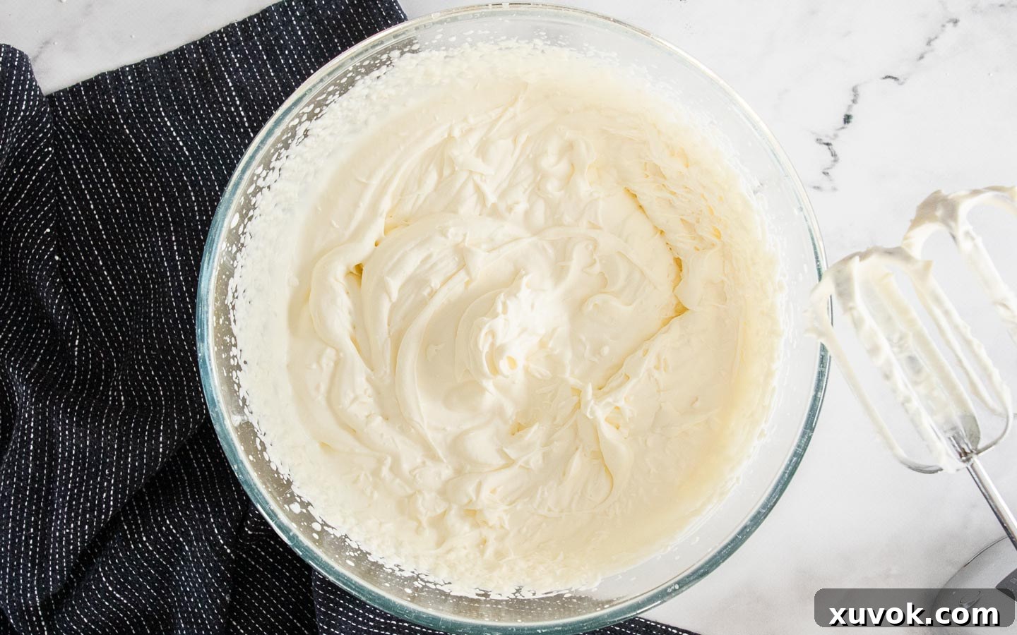 Whipped cream in a bowl reaching soft peaks, perfectly light and airy.