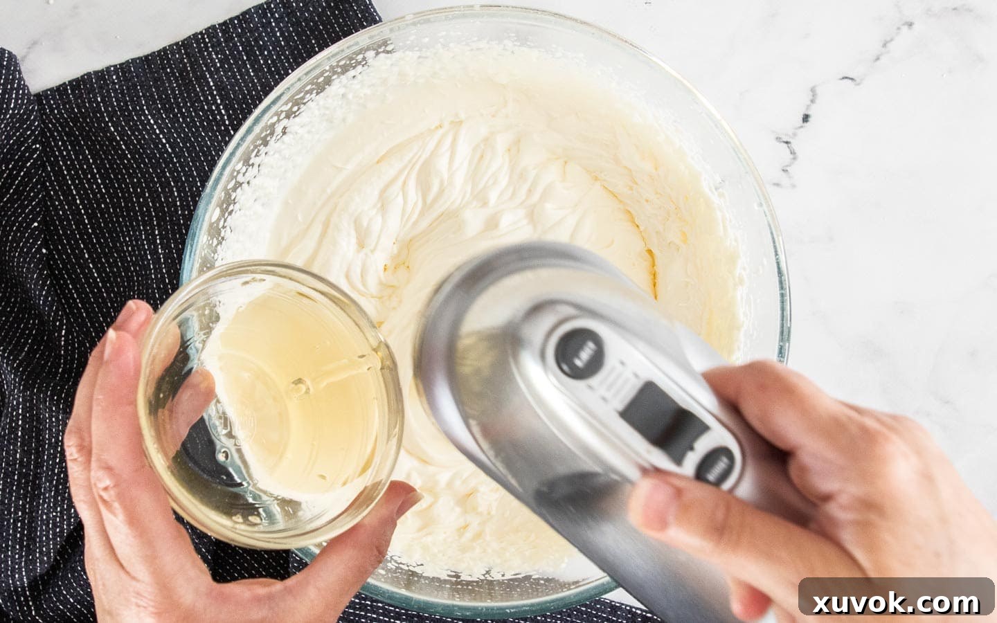 Gelatine mixture being slowly poured into whipped cream with the mixer running.