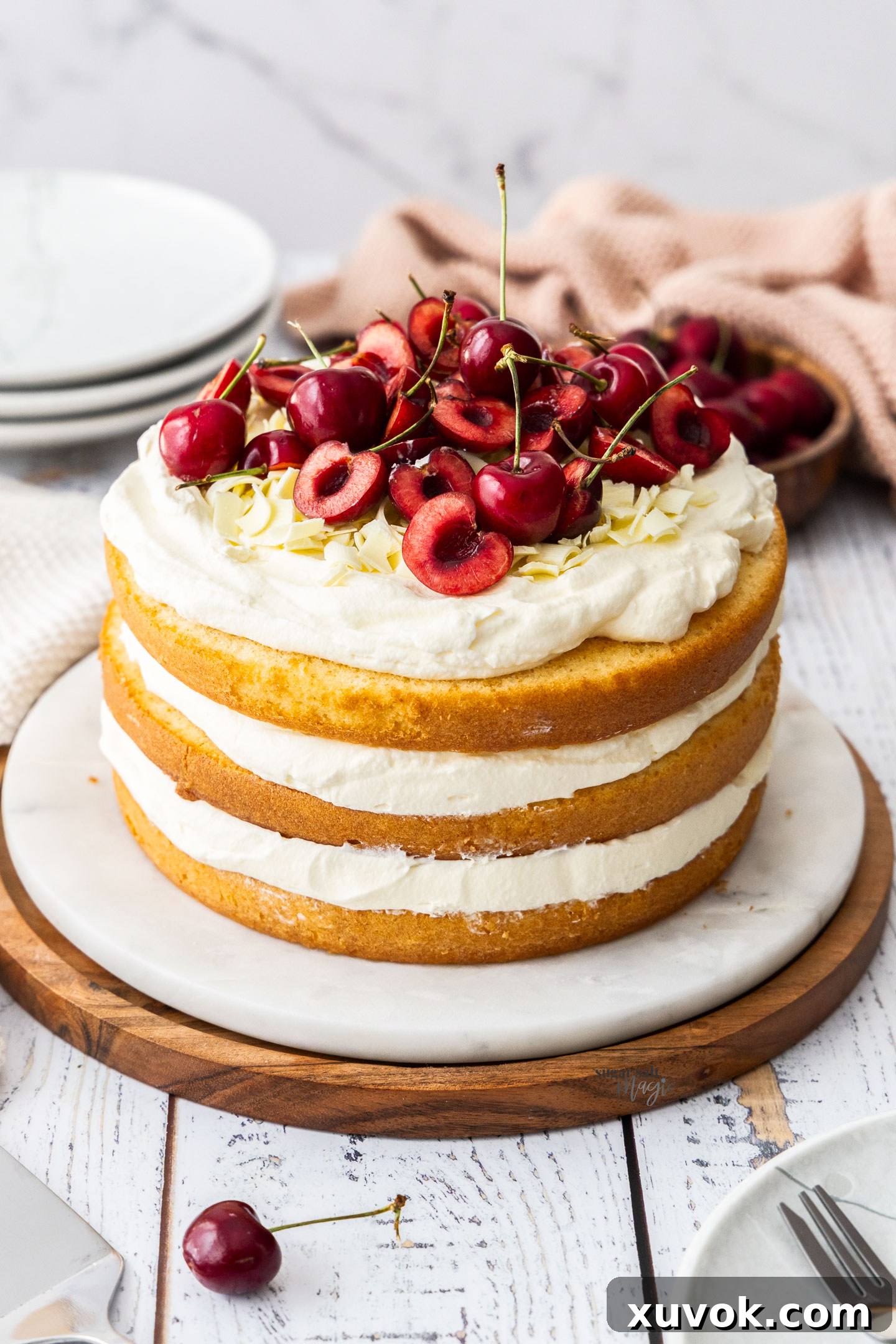 A beautifully assembled 3-layer white forest cake with vanilla cream and cherry filling on a cake platter.