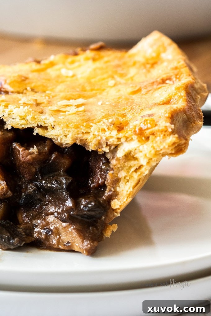 Closeup of the side of a slice of beef pie showing the beautiful flaky texture of the pastry.