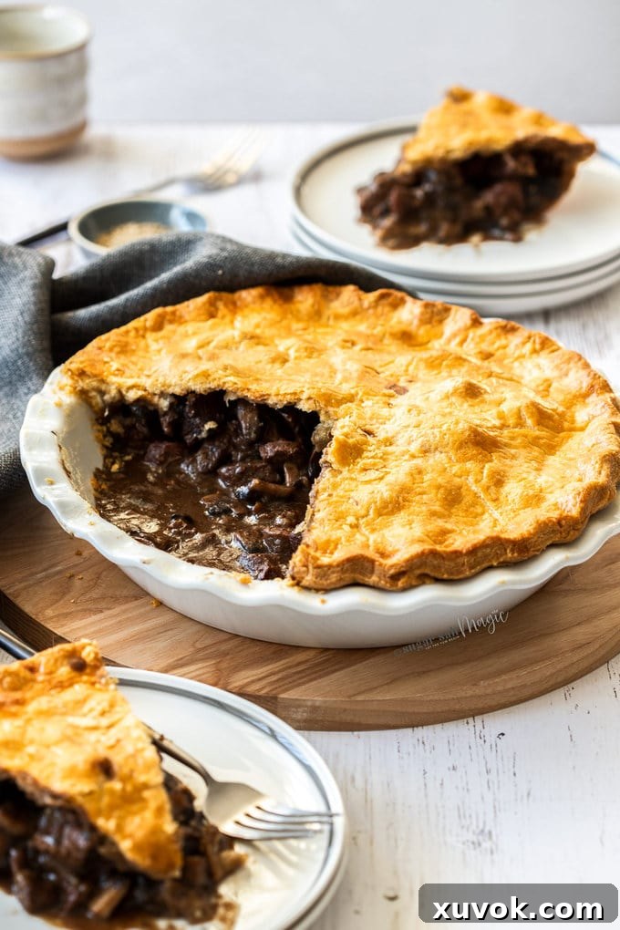 Beef pie in a white pie dish, showcasing the hearty filling and golden crust. It sits on a rustic wooden board.