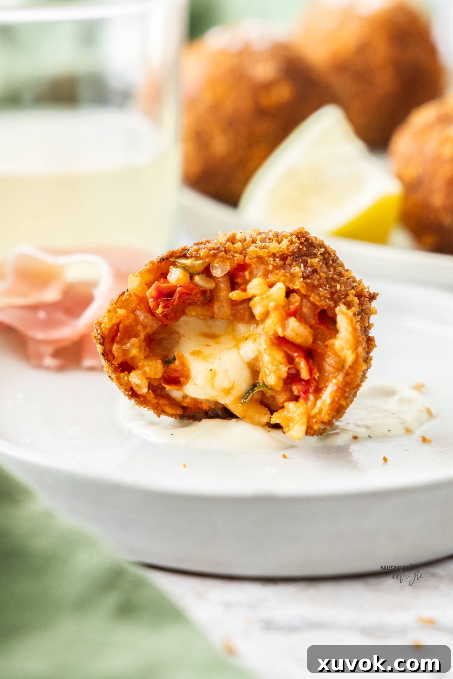 A close-up shot of a tomato arancino cut in half, showcasing its crispy exterior and gooey, melted mozzarella center.