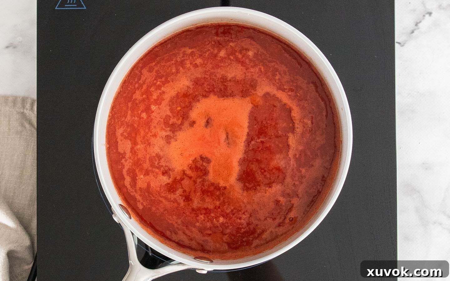 The tomato and vegetable stock mixture simmering gently in a saucepan.