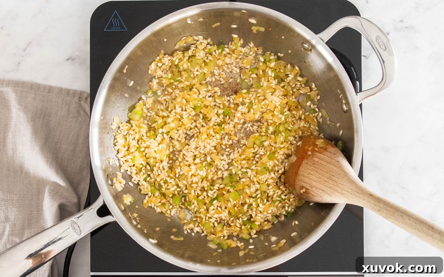 Arborio rice added to the pan with sautéed vegetables, beginning to look glassy.