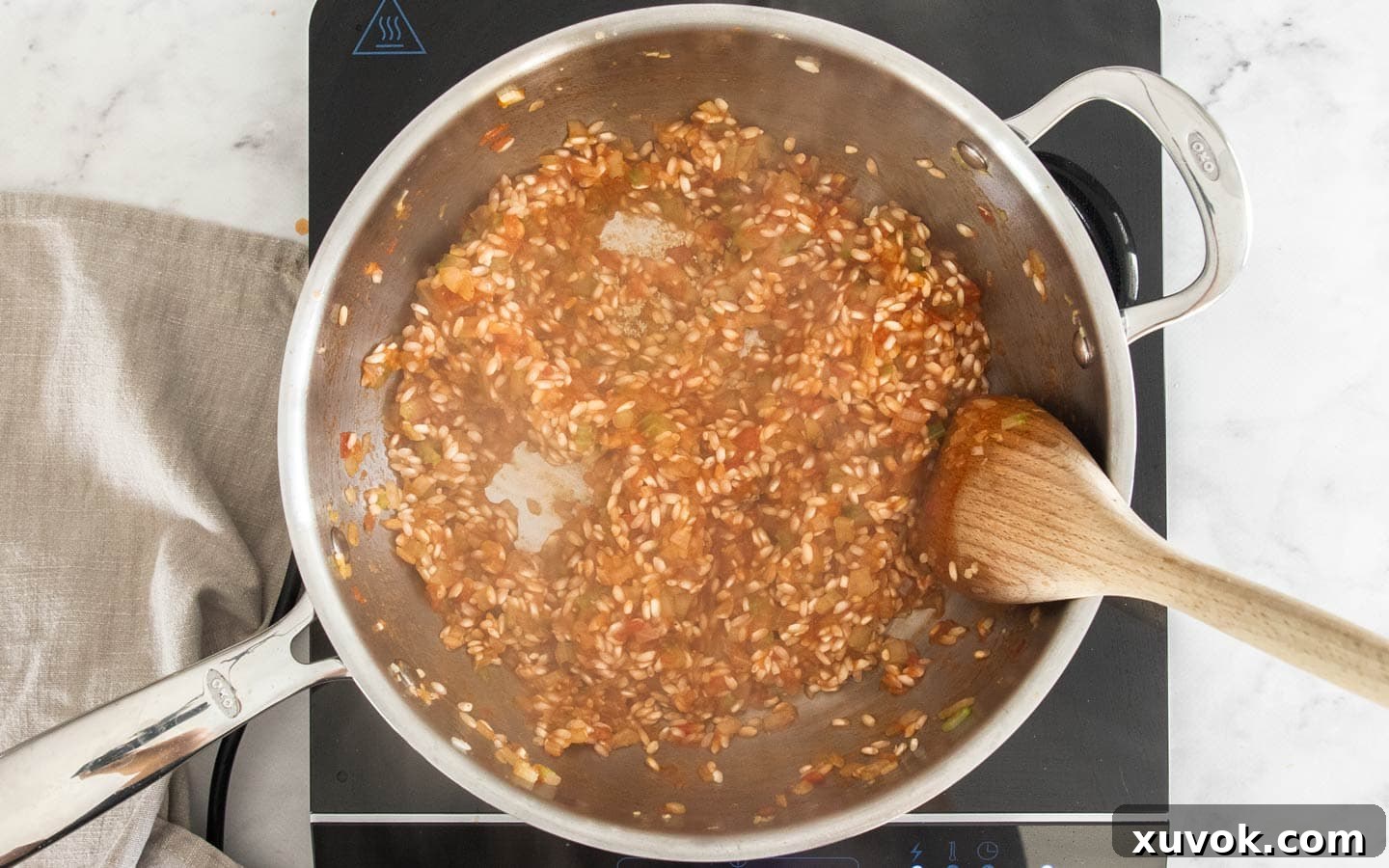 The rice with the first ladleful of tomato stock being absorbed in the pan.