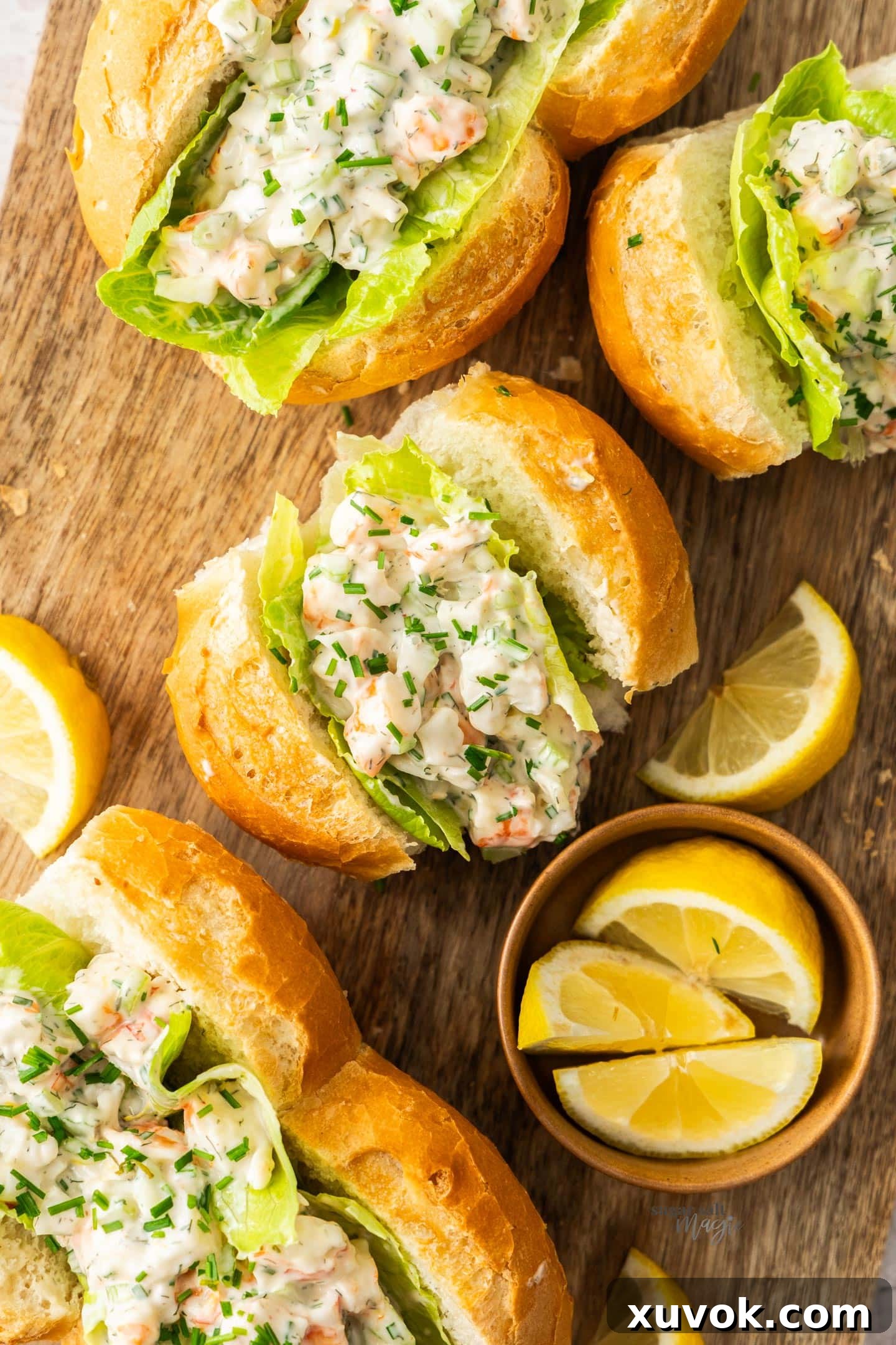 Four creamy prawn rolls, perfectly arranged on a rustic wooden board, ready to be served.
