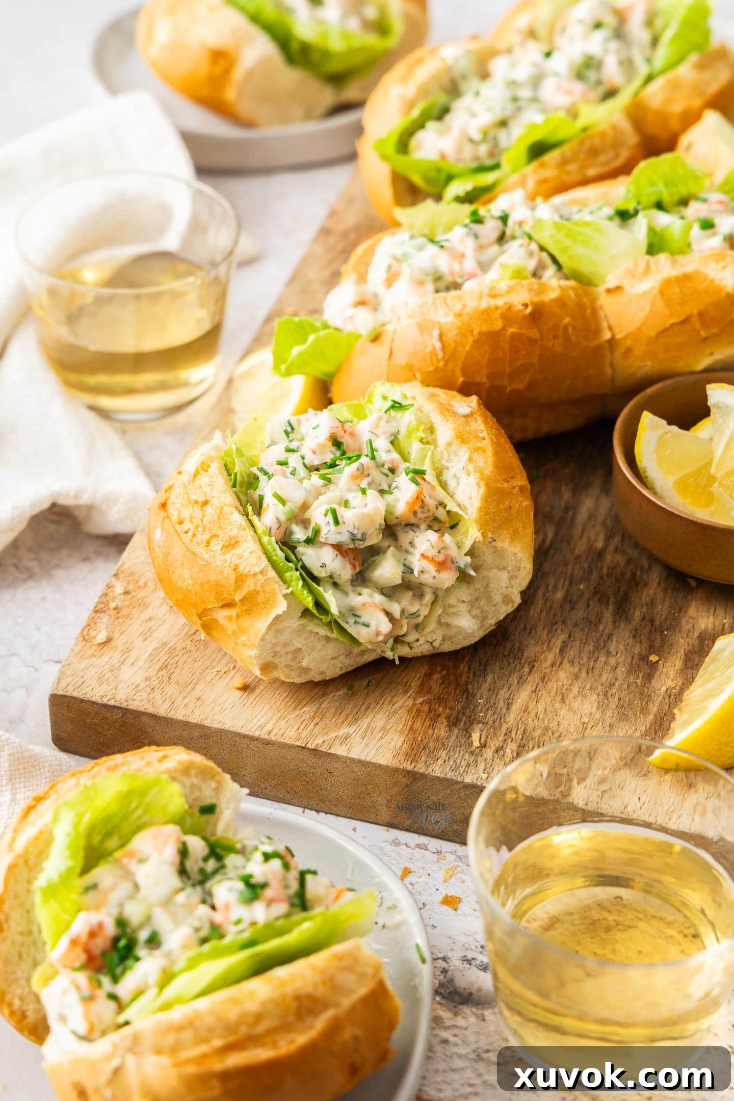 A batch of deliciously prepared prawn rolls resting on a wooden board, with one invitingly placed on a small white plate in the foreground.