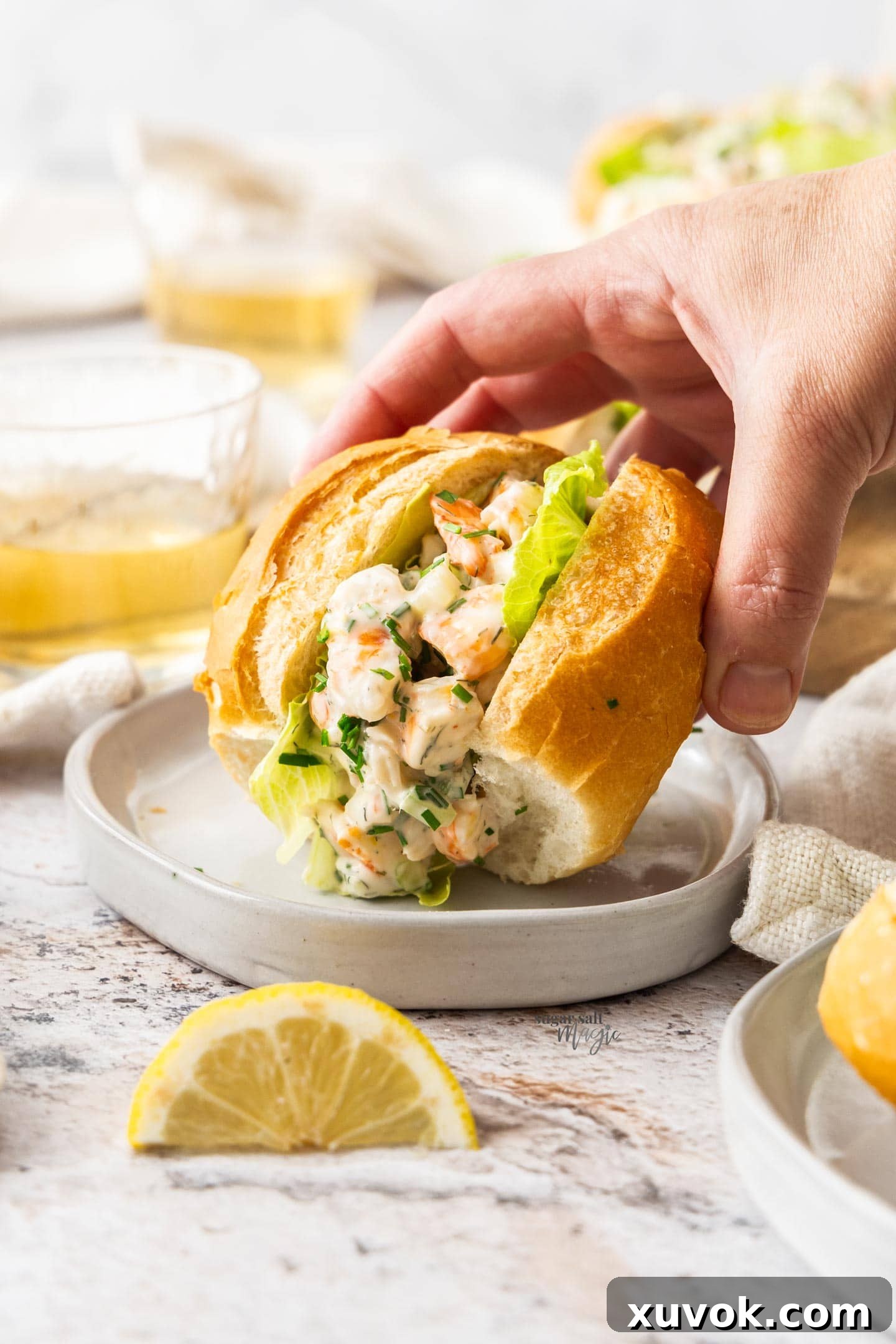 A hand reaches in to pick up a perfectly crafted prawn slider from a wooden serving board, showcasing its enticing filling.