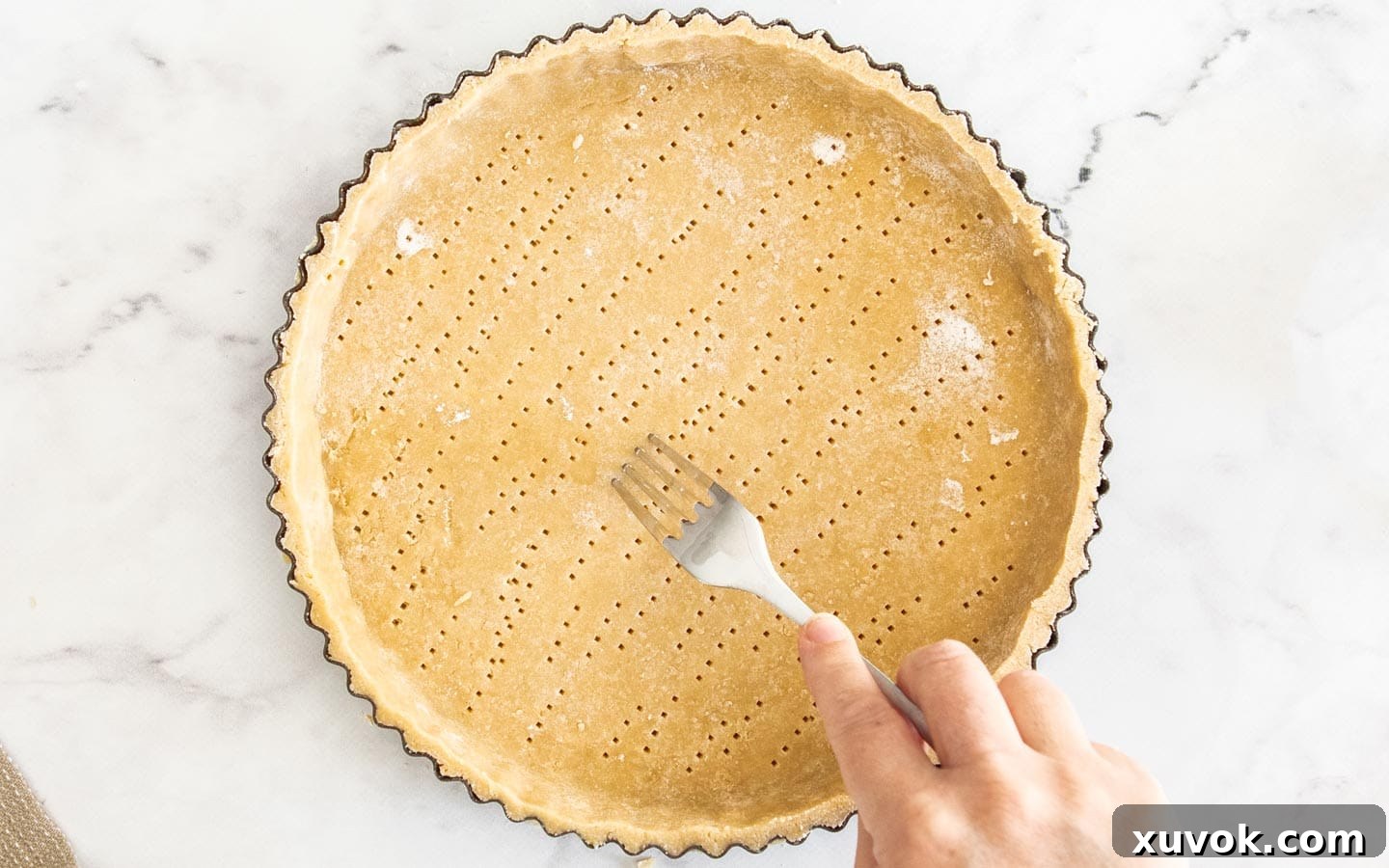 The pastry crust being docked with a fork.