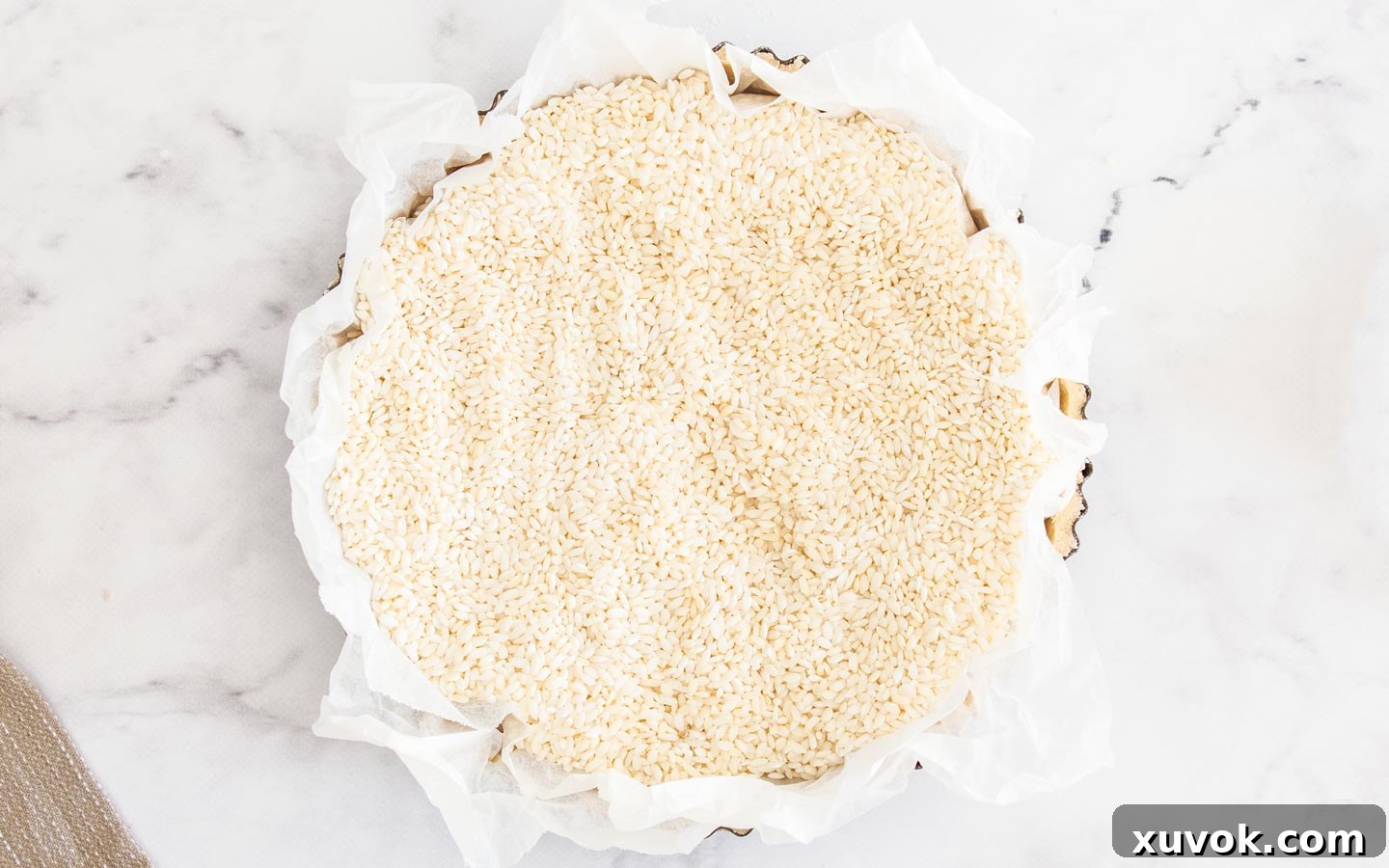 The raw tart shell filled with baking paper and rice.