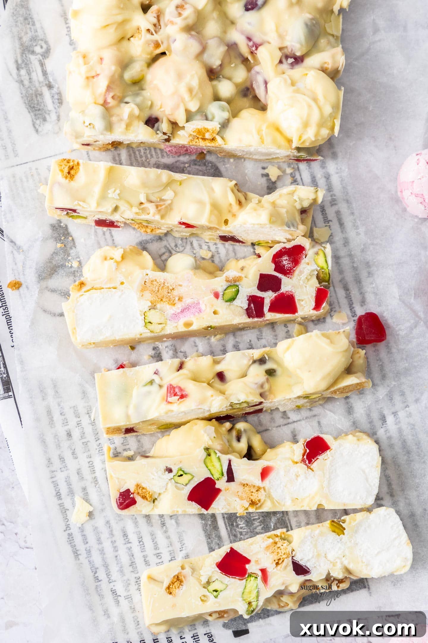 Top down view of a tray of white chocolate rocky road cut into neat slices, revealing the colorful fillings.