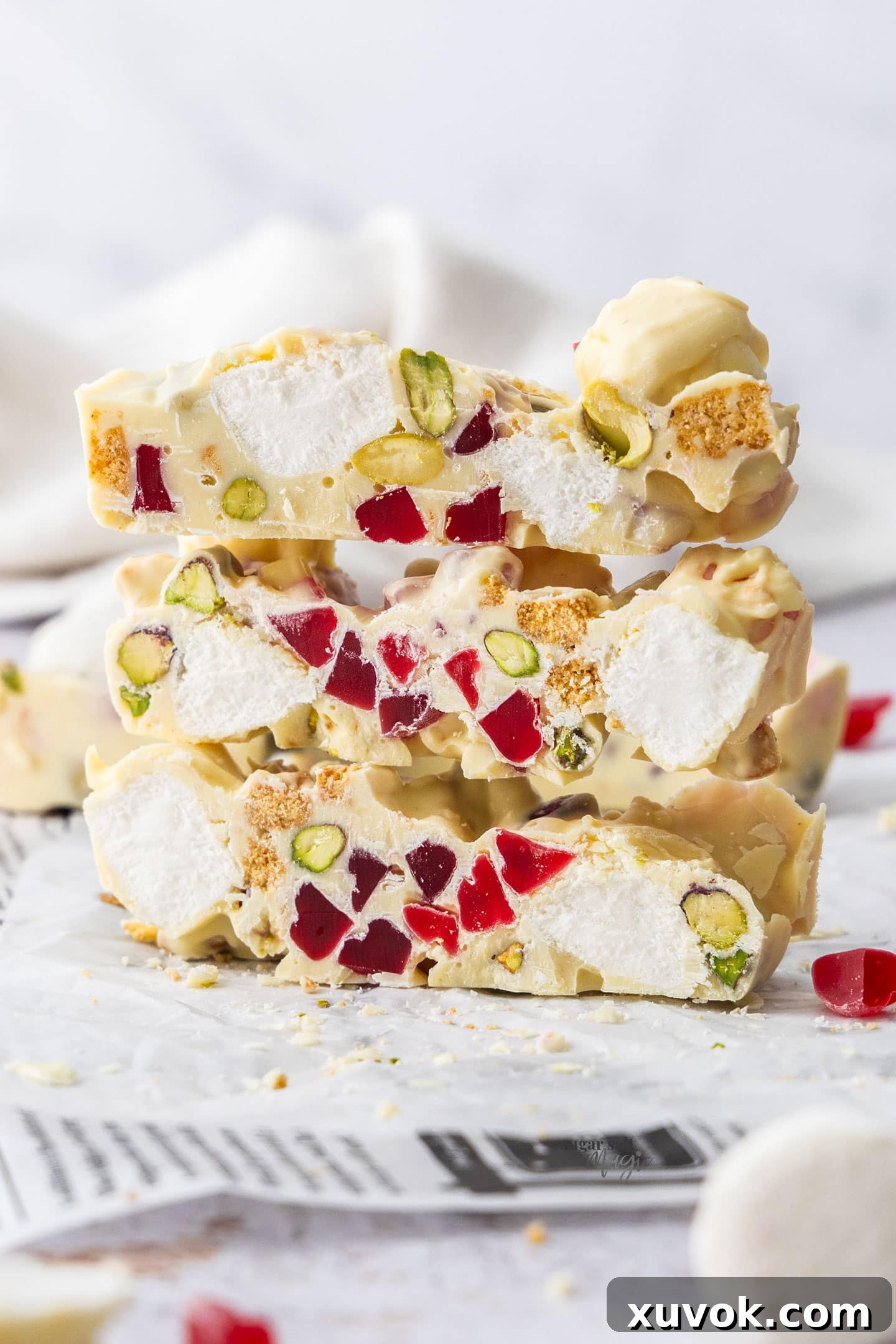 Three slices of white chocolate rocky road stacked aesthetically one on top of the other.