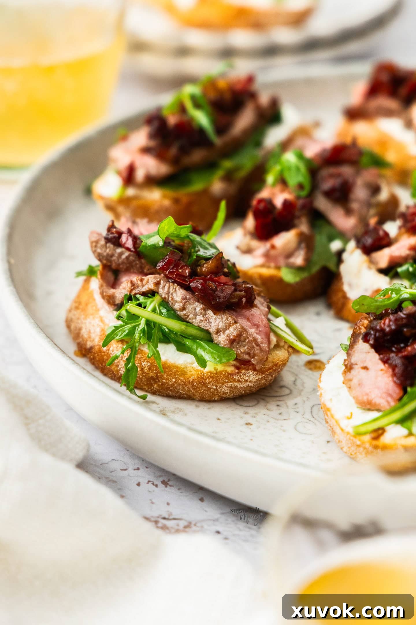 Closeup of a single steak crostini with rocket and sun dried tomatoes.