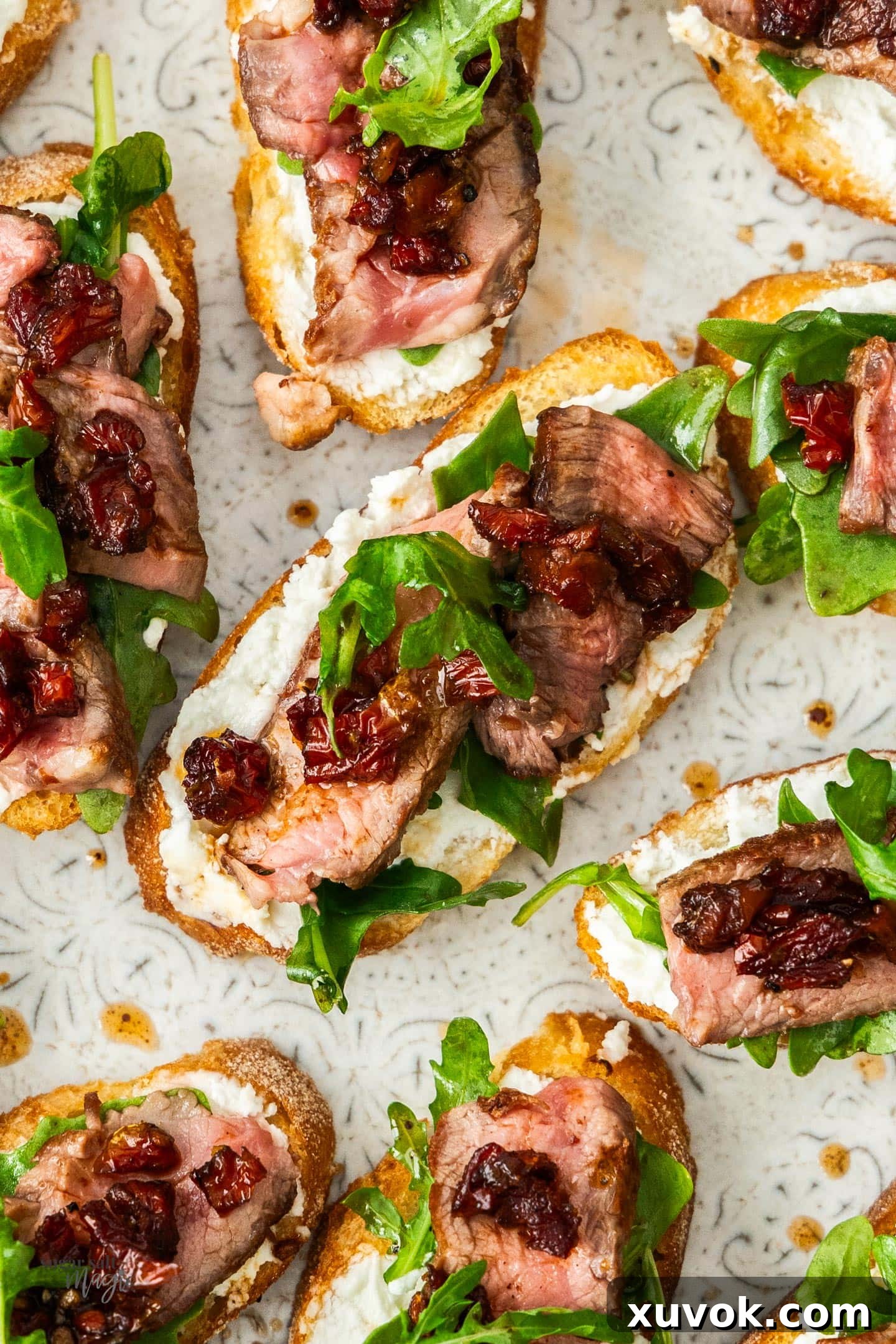 Top down view of a steak crostini on a platter with more surrounding it.