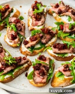 A batch of crostini topped with goats cheese and steak.