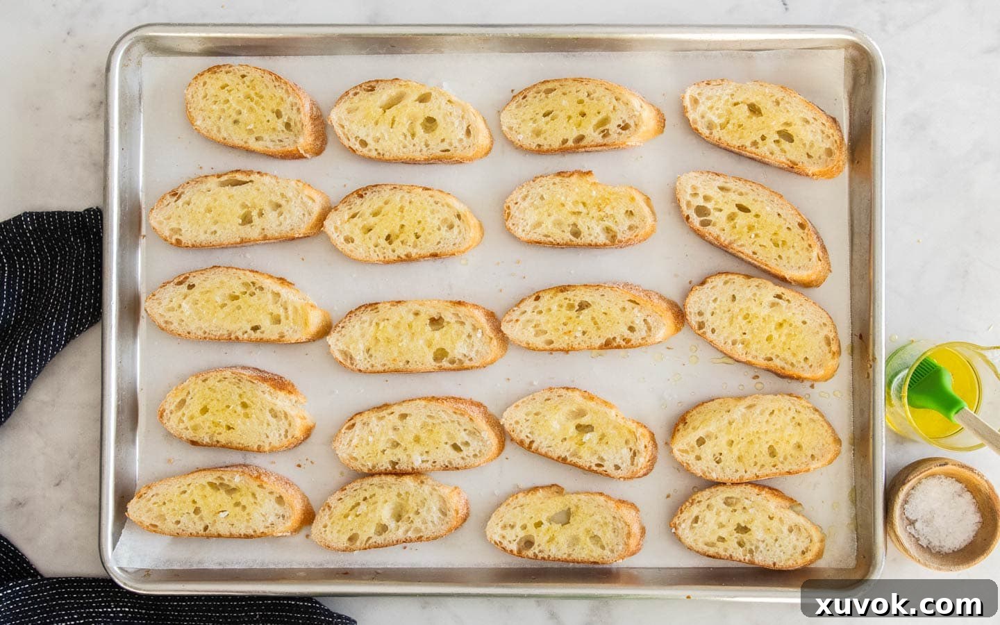 Slices of baguette, brushed with oil on a baking sheet.