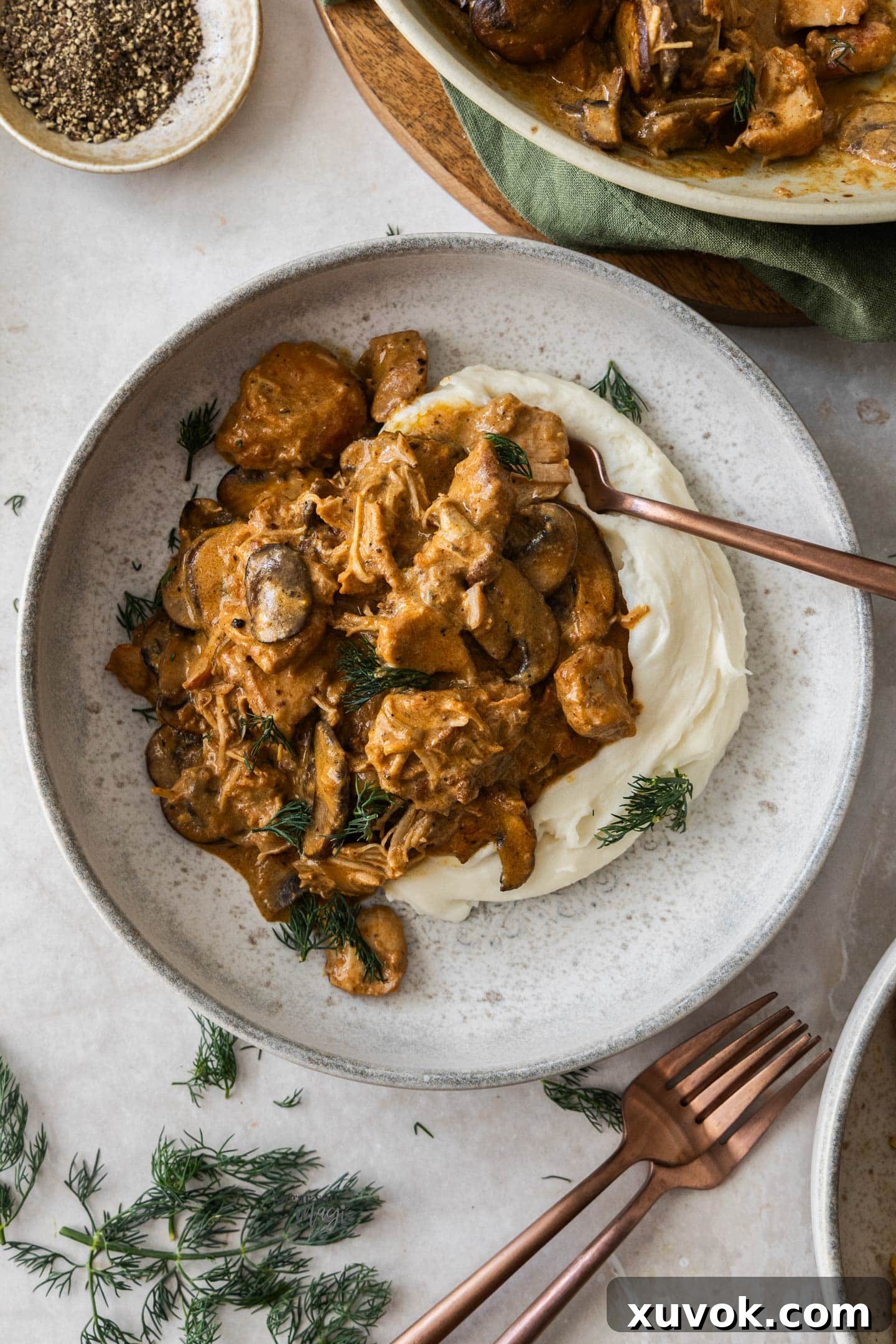 Chicken stroganoff served over creamy mashed potatoes in a bowl.