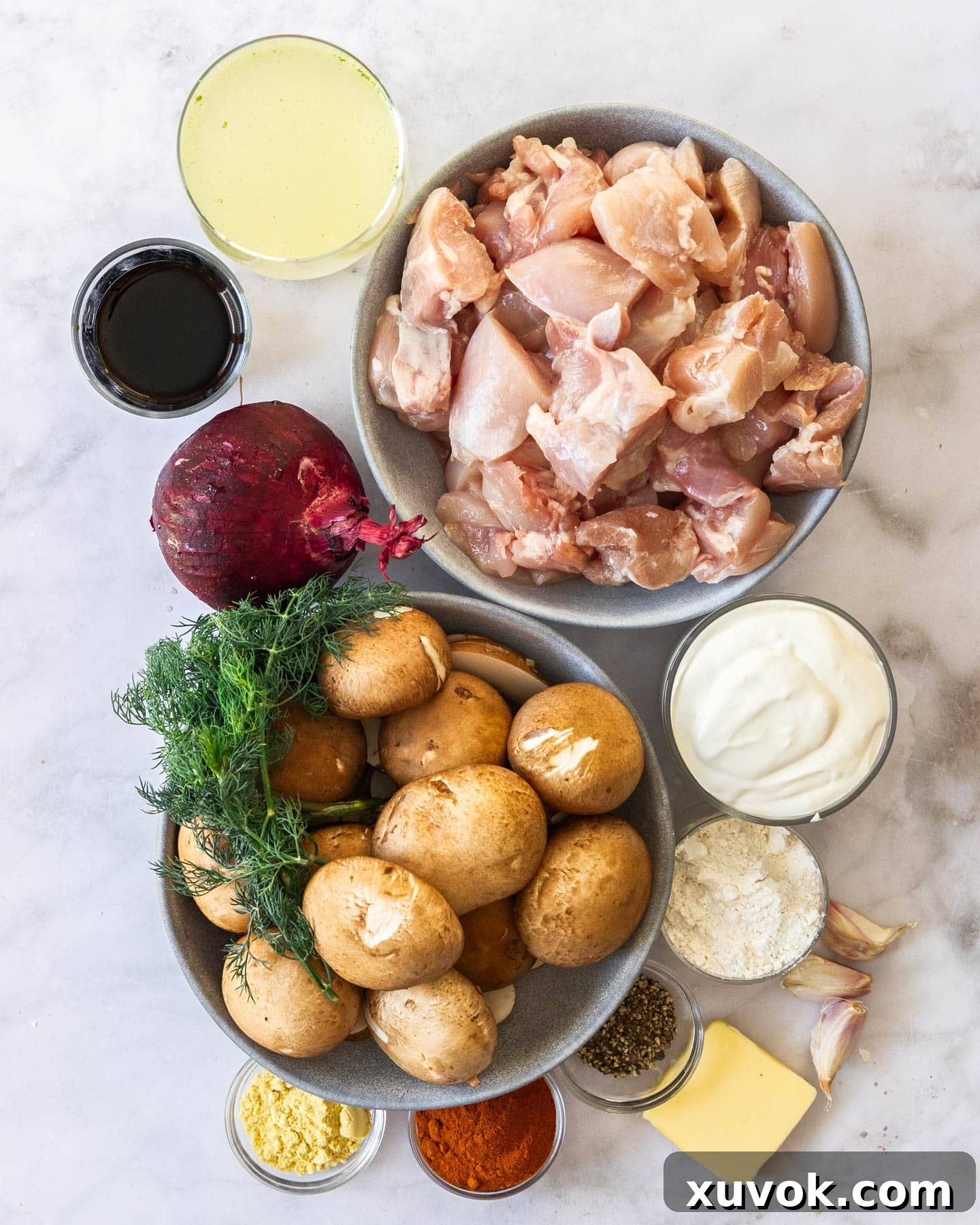 A flat lay image showing all the fresh ingredients for slow cooked chicken stroganoff on a wooden board.