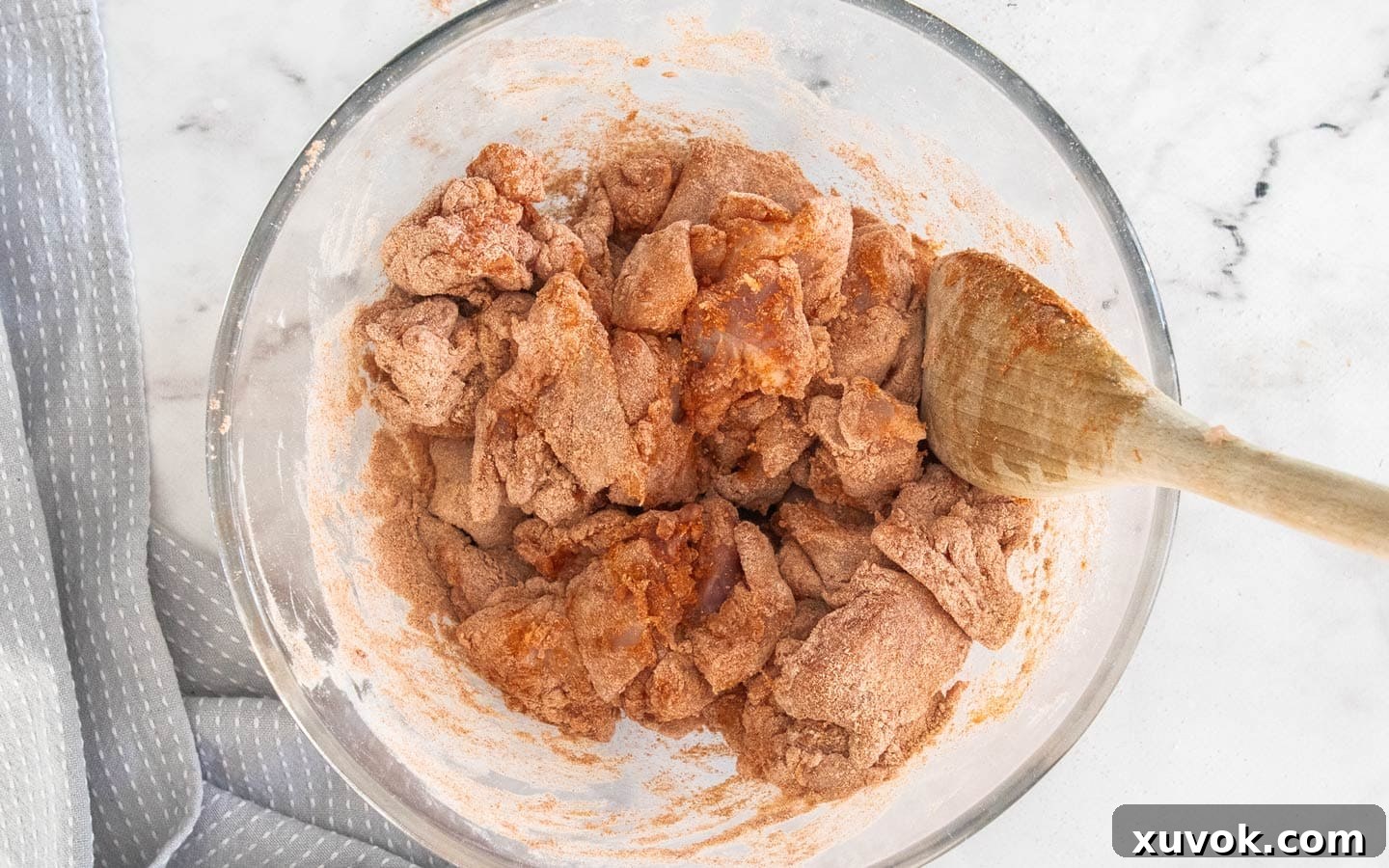 The chicken pieces coated in seasoning and flour in a mixing bowl.